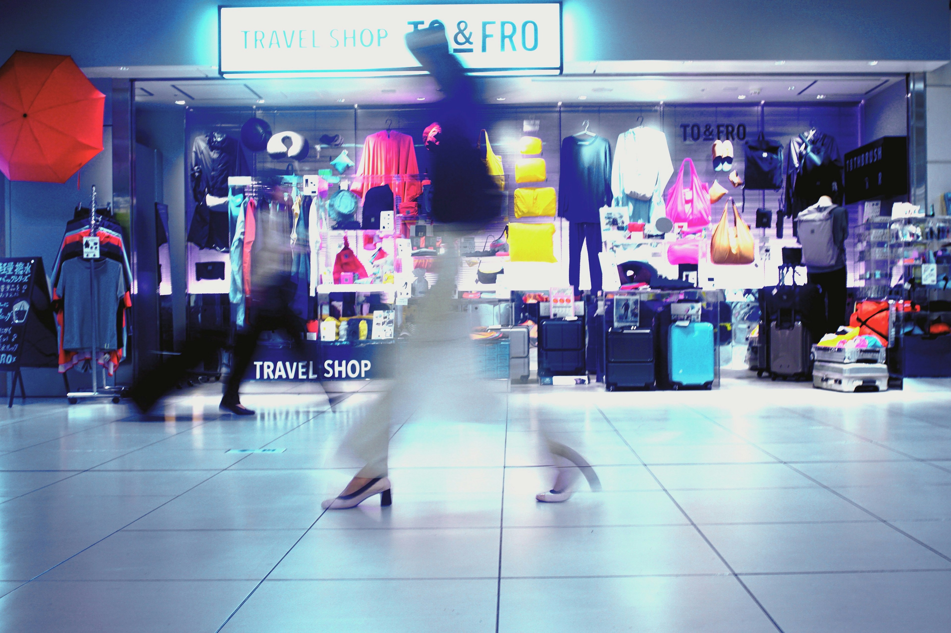 Une vitrine de centre commercial animée avec des marchandises colorées et des silhouettes floues de personnes