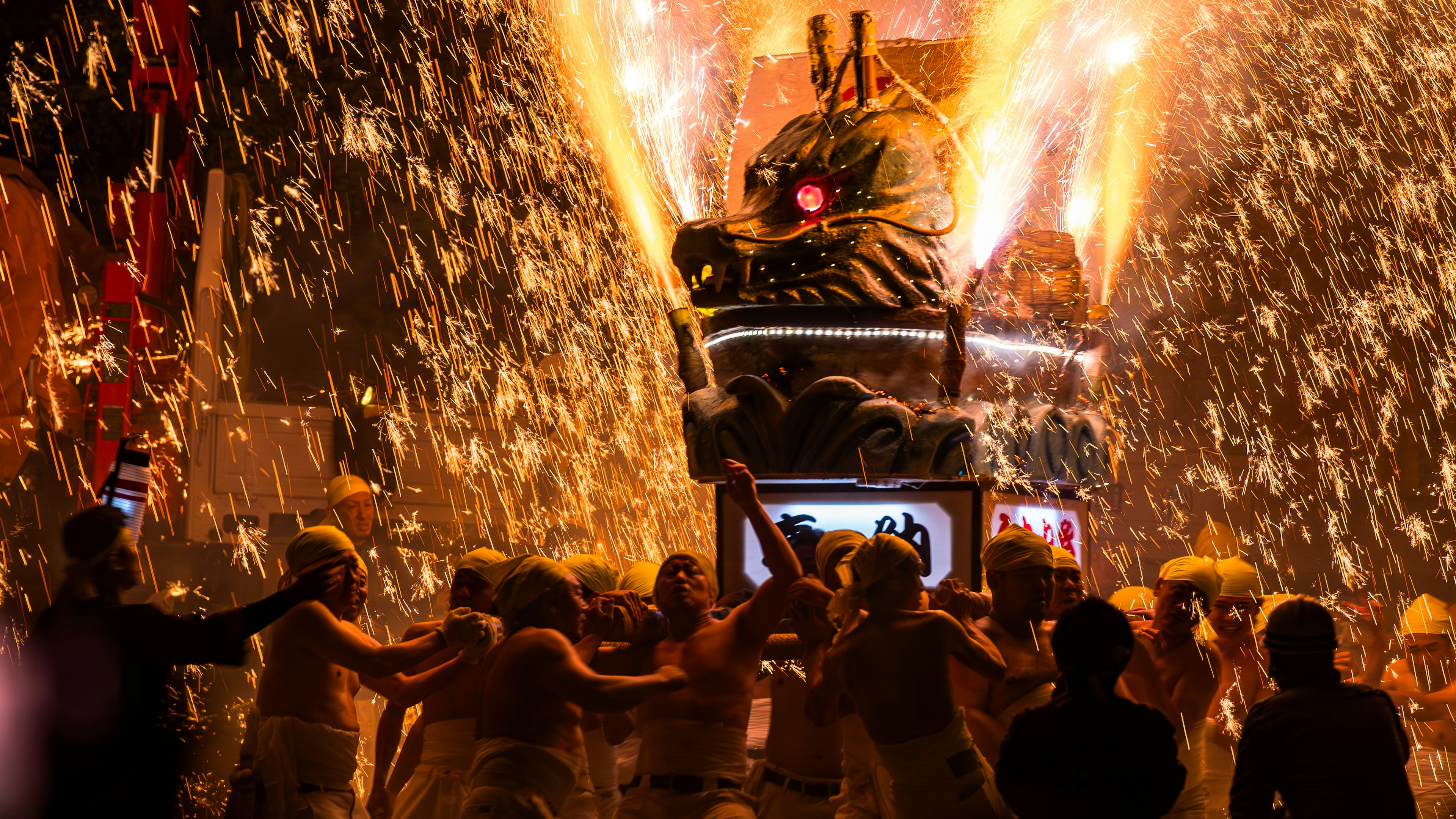 Vibrant festival scene with sparks and water splashes as participants dance around a lion dance float