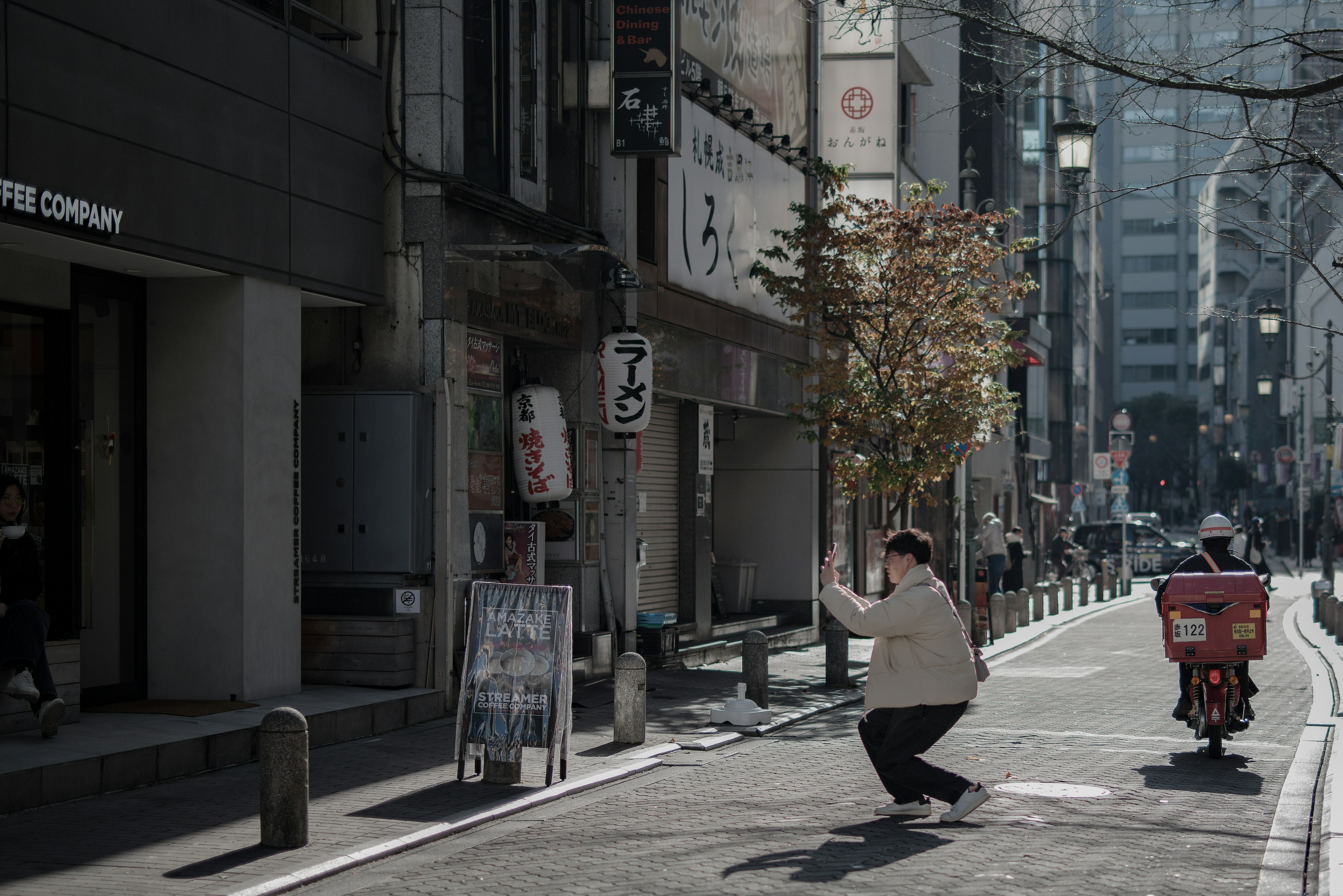 A person in motion on a street in Tokyo with a bicycle delivery nearby