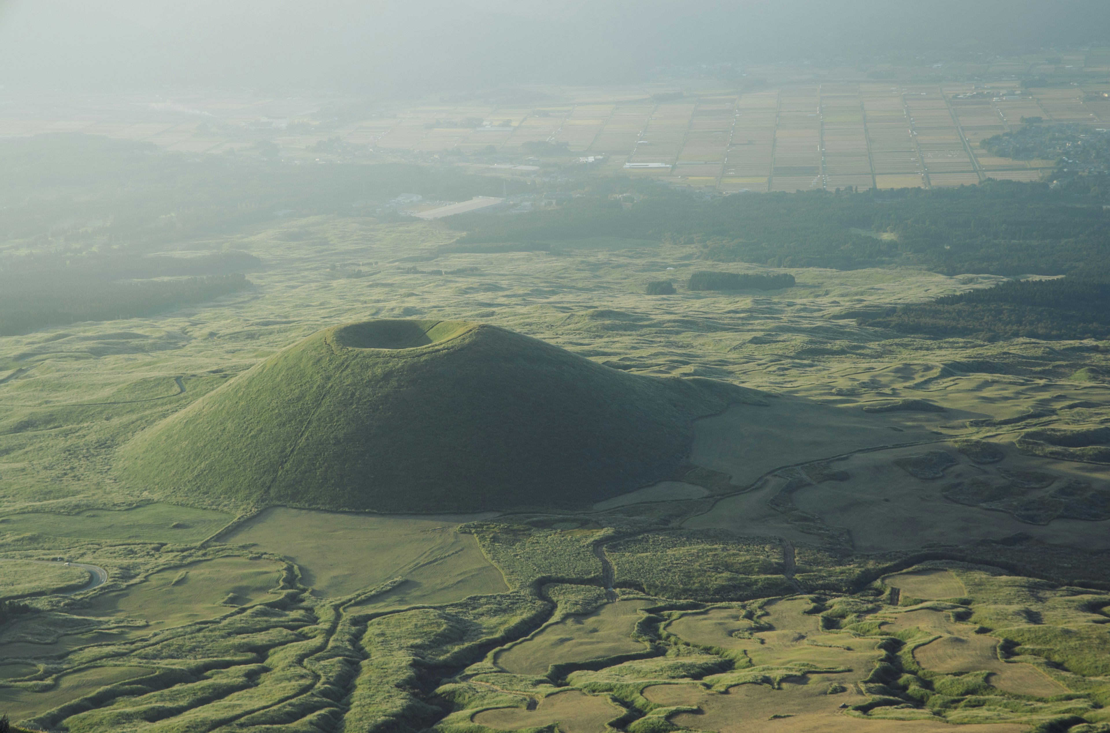 Pemandangan udara gunung berapi berbentuk kerucut yang ditutupi rumput hijau