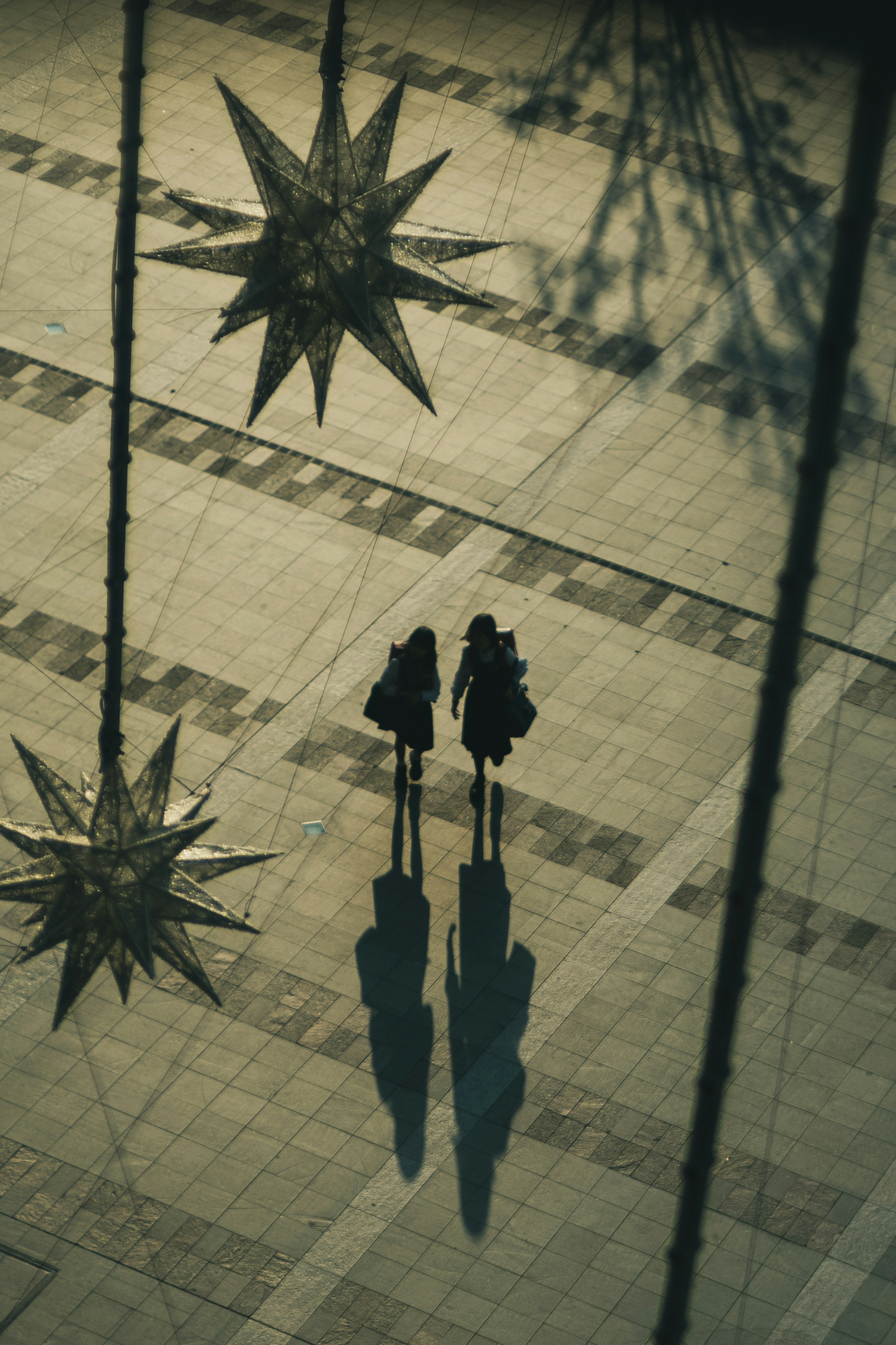 Siluetas de dos personas debajo de decoraciones en forma de estrella en una calle de la ciudad