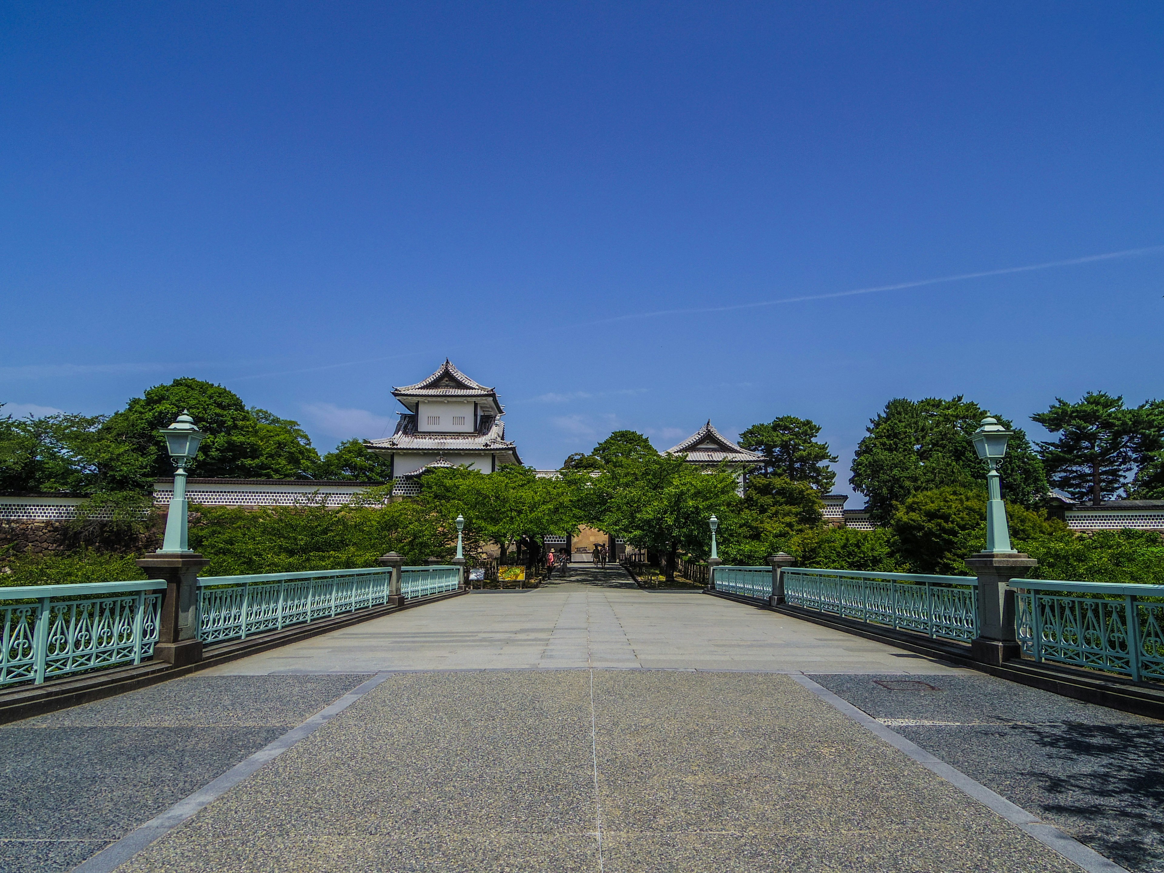 Malersicher Blick auf eine Brücke, die zu einem Schloss unter klarem blauen Himmel führt