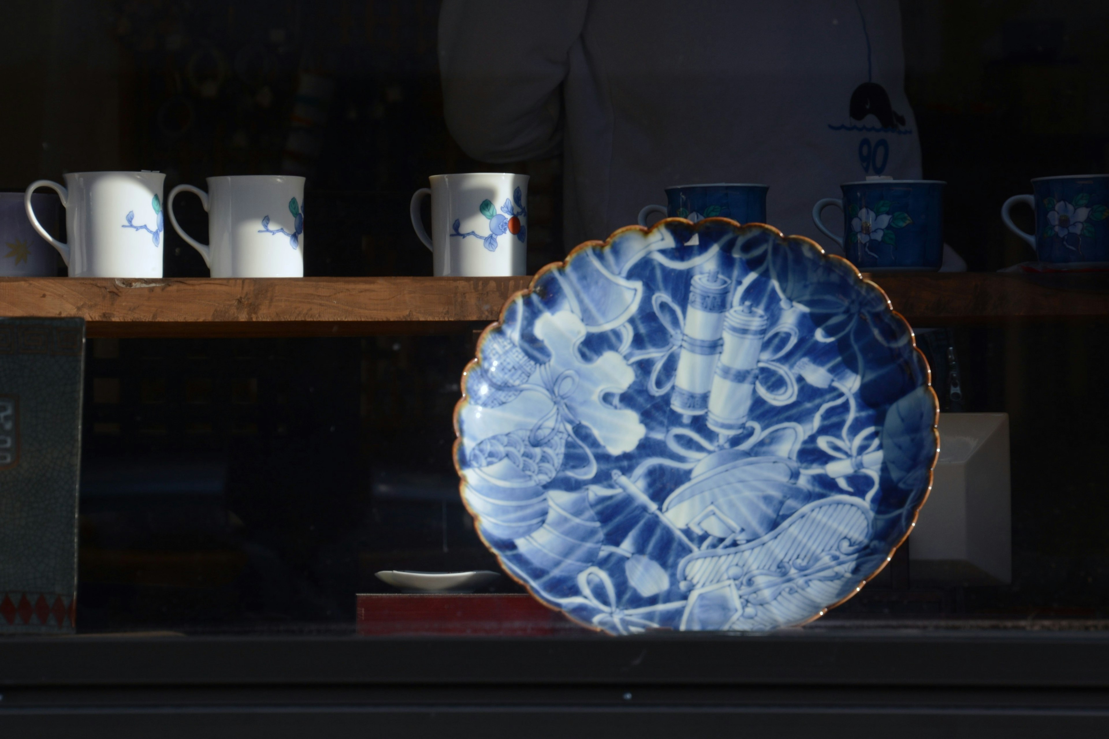 Un plato de cerámica azul en primer plano con tazas blancas de fondo