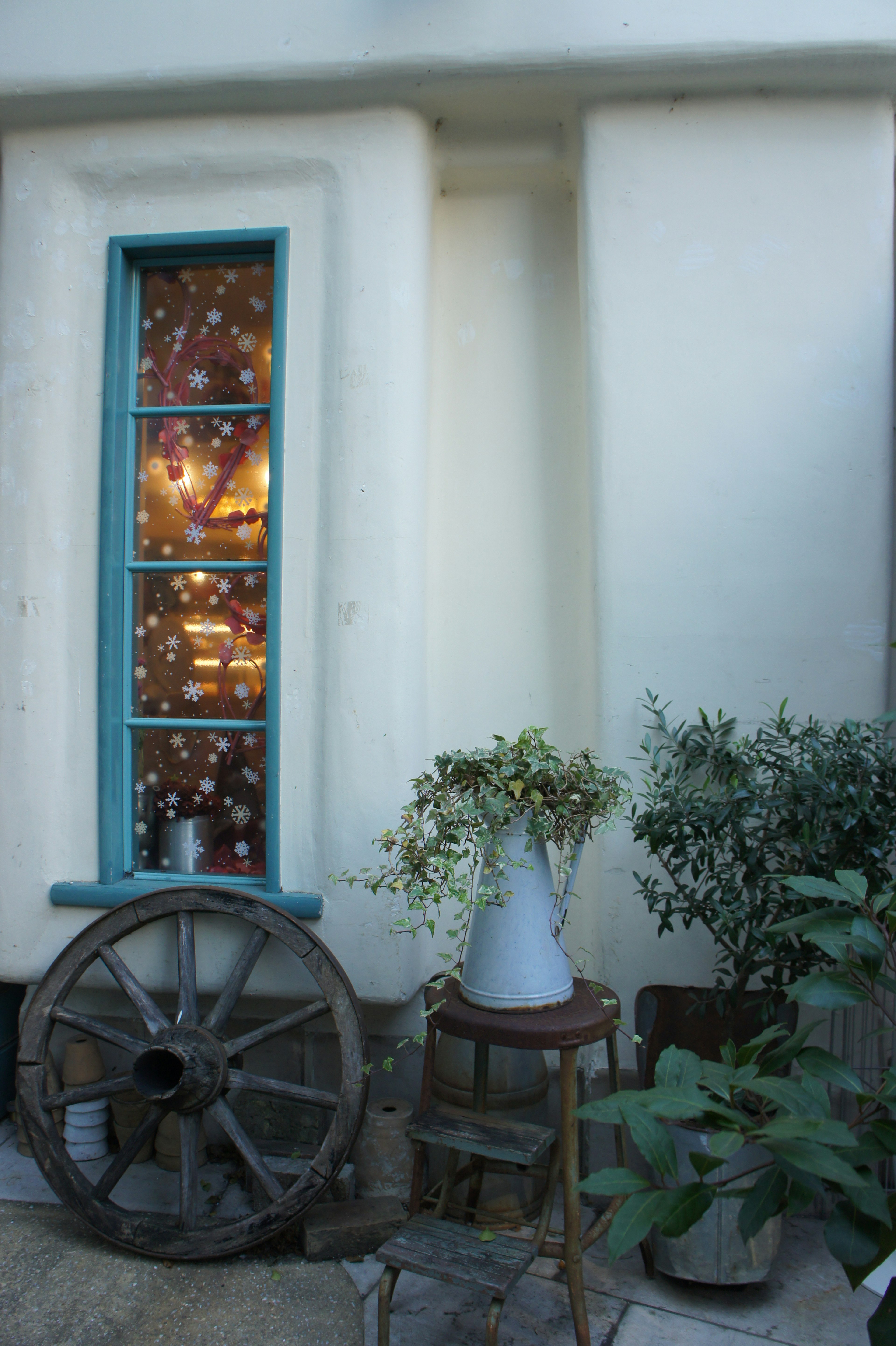 Exterior de una casa con marco de ventana azul y plantas en maceta