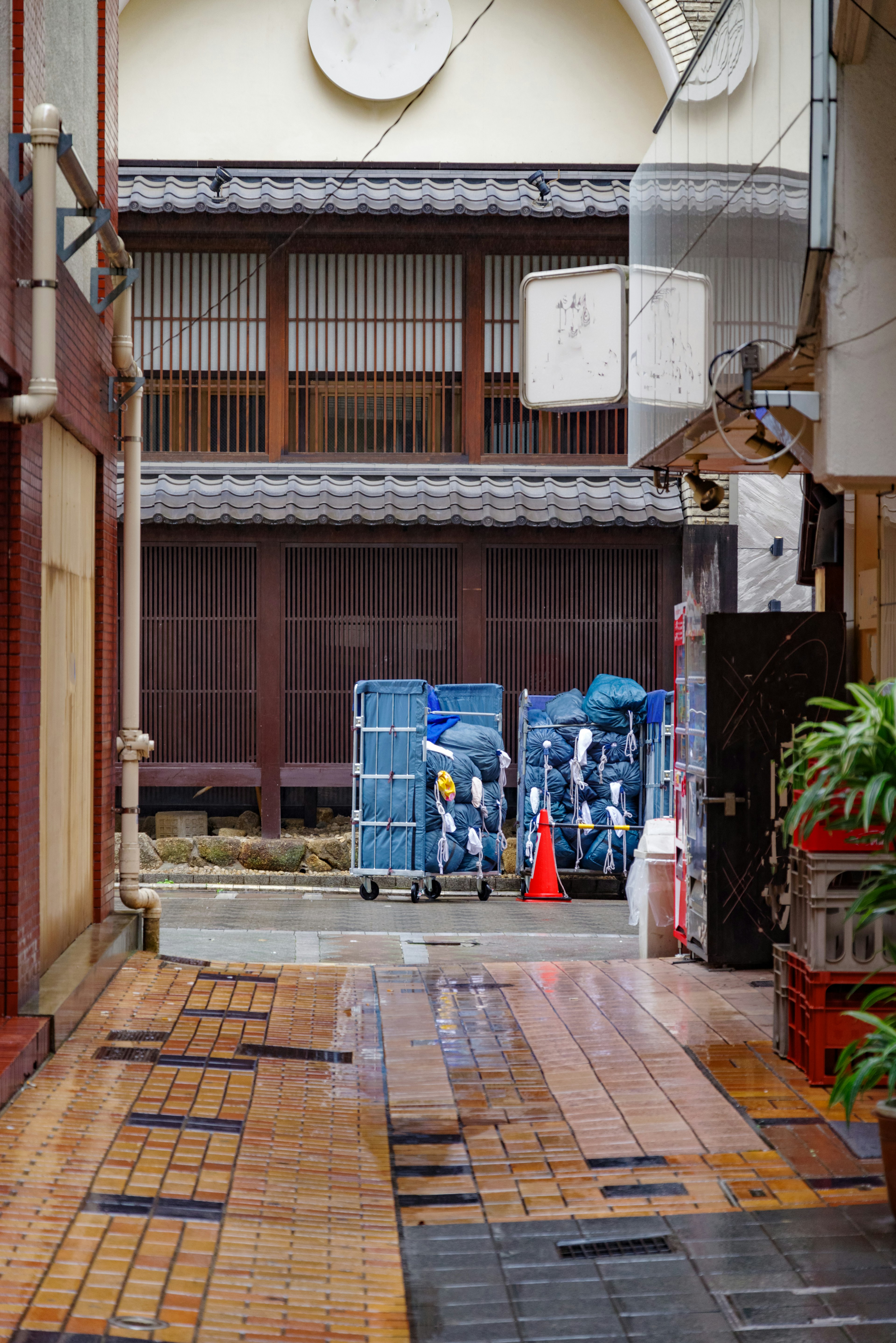 Narrow alley featuring blue carts and an orange cone