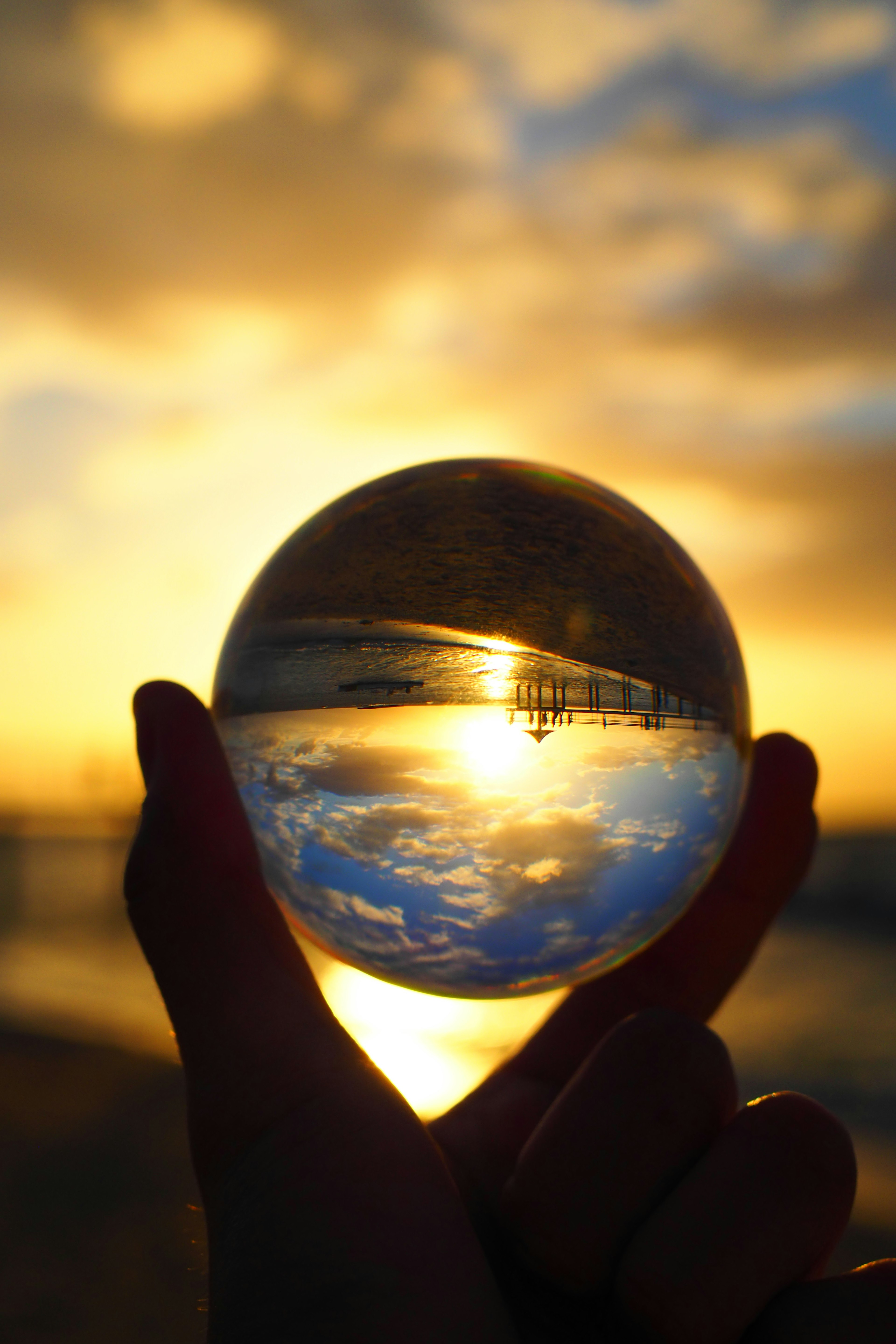 Hand hält eine Kristallkugel, die den Sonnenuntergang reflektiert