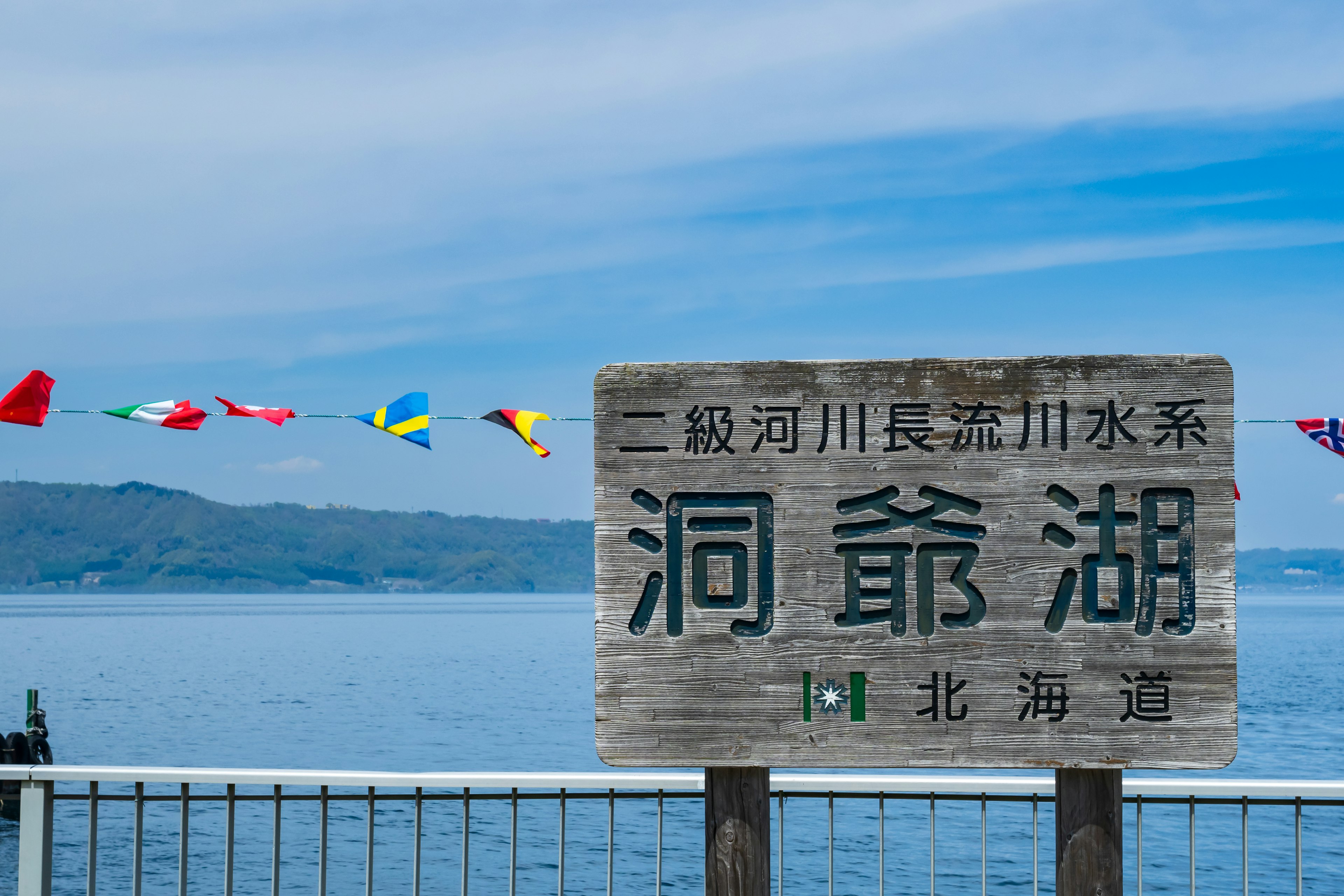 Sign for the lake with colorful flags in the background