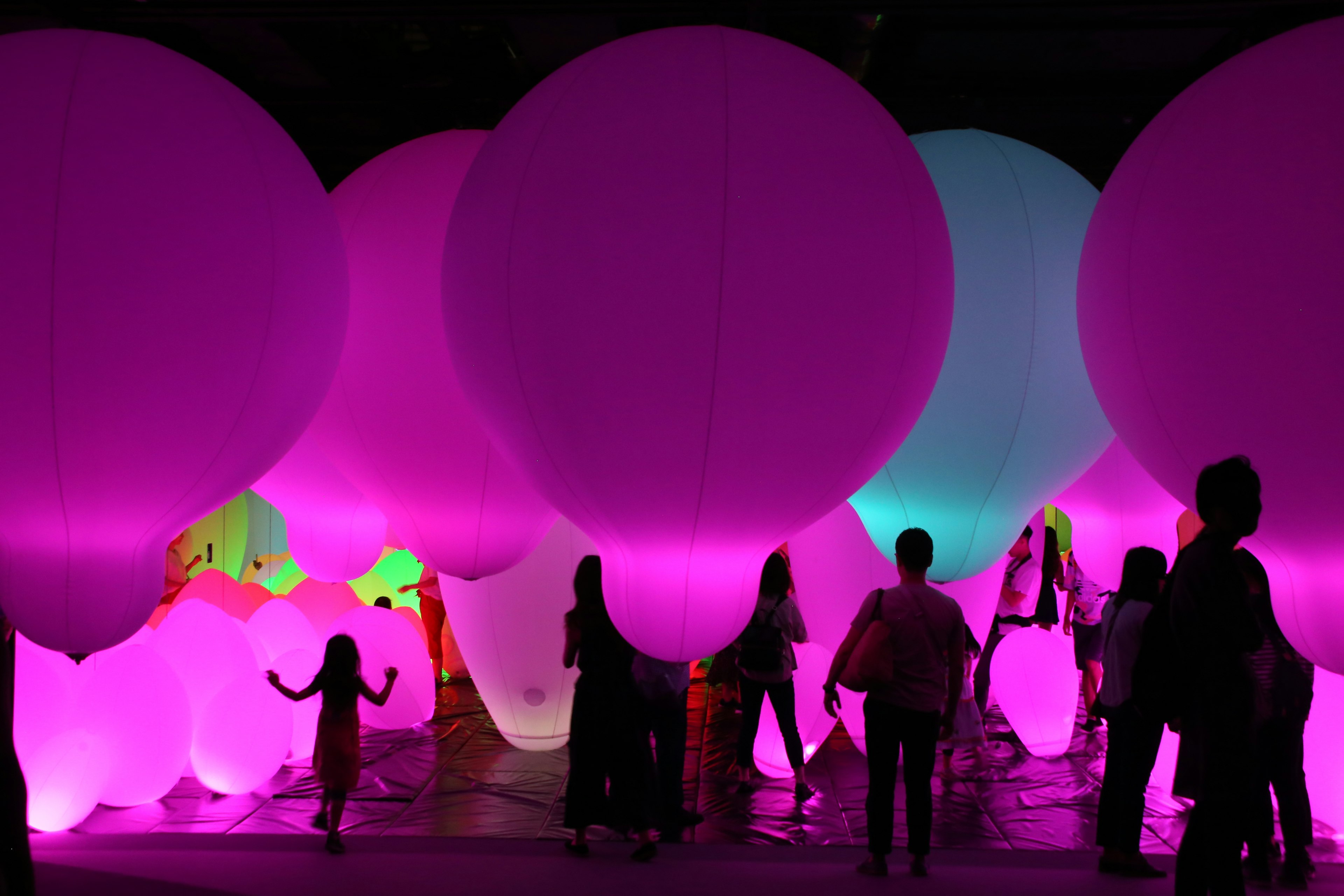 Silhouette orang-orang bermain di antara balon besar yang berwarna-warni