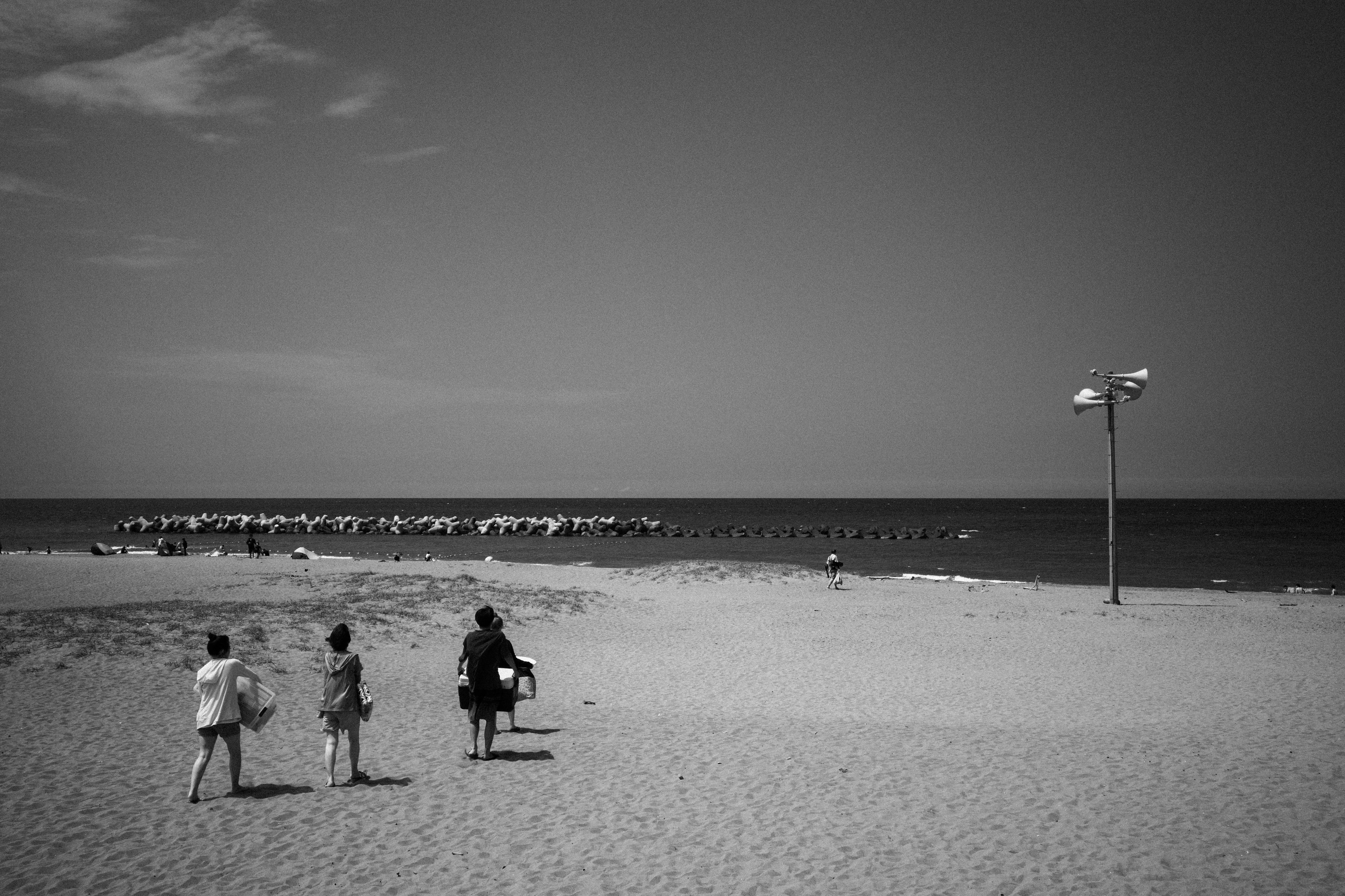 Tres niños caminando hacia la playa con un mar tranquilo de fondo