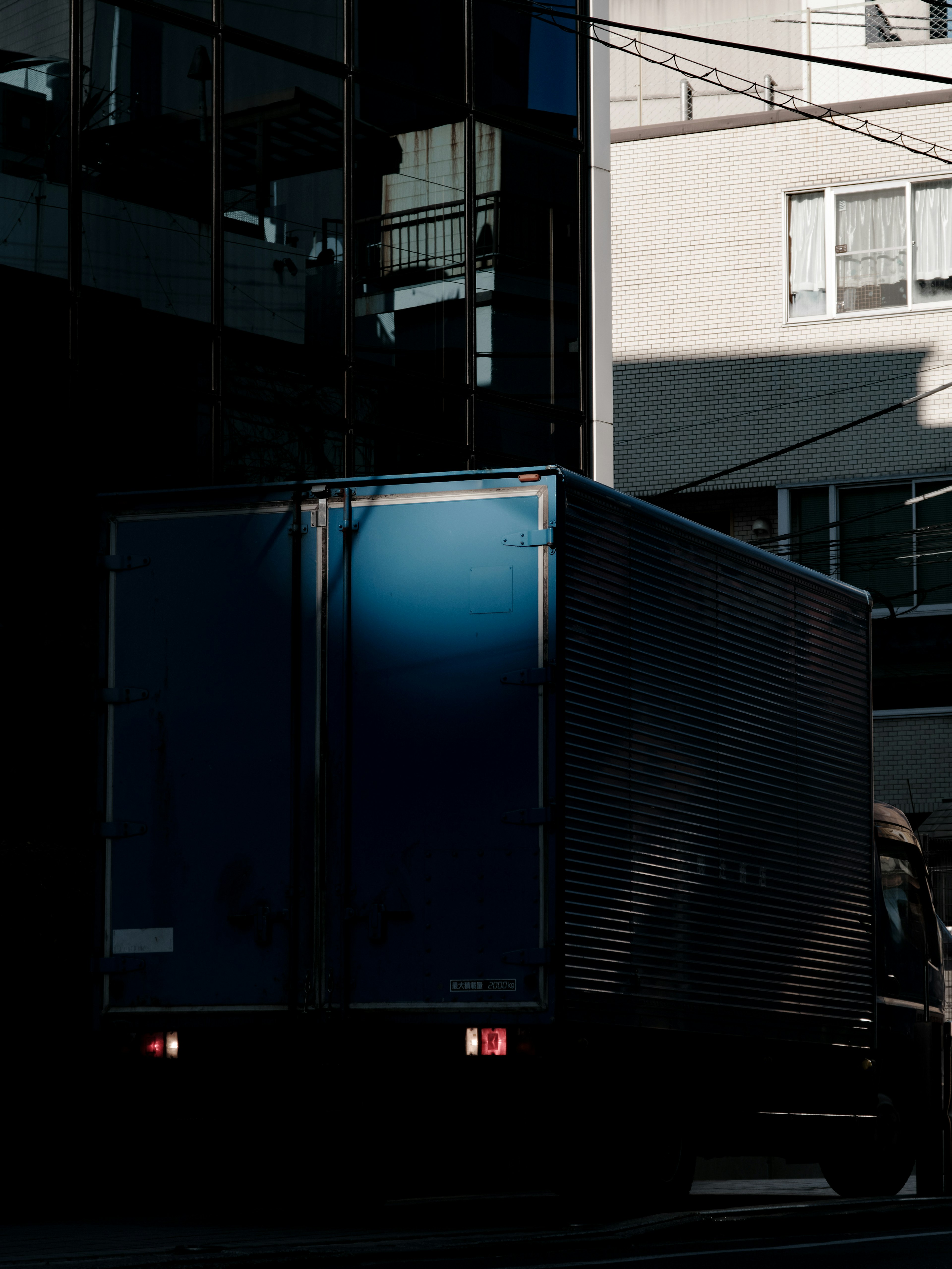 Blauer Lastwagen im Schatten eines Gebäudes geparkt