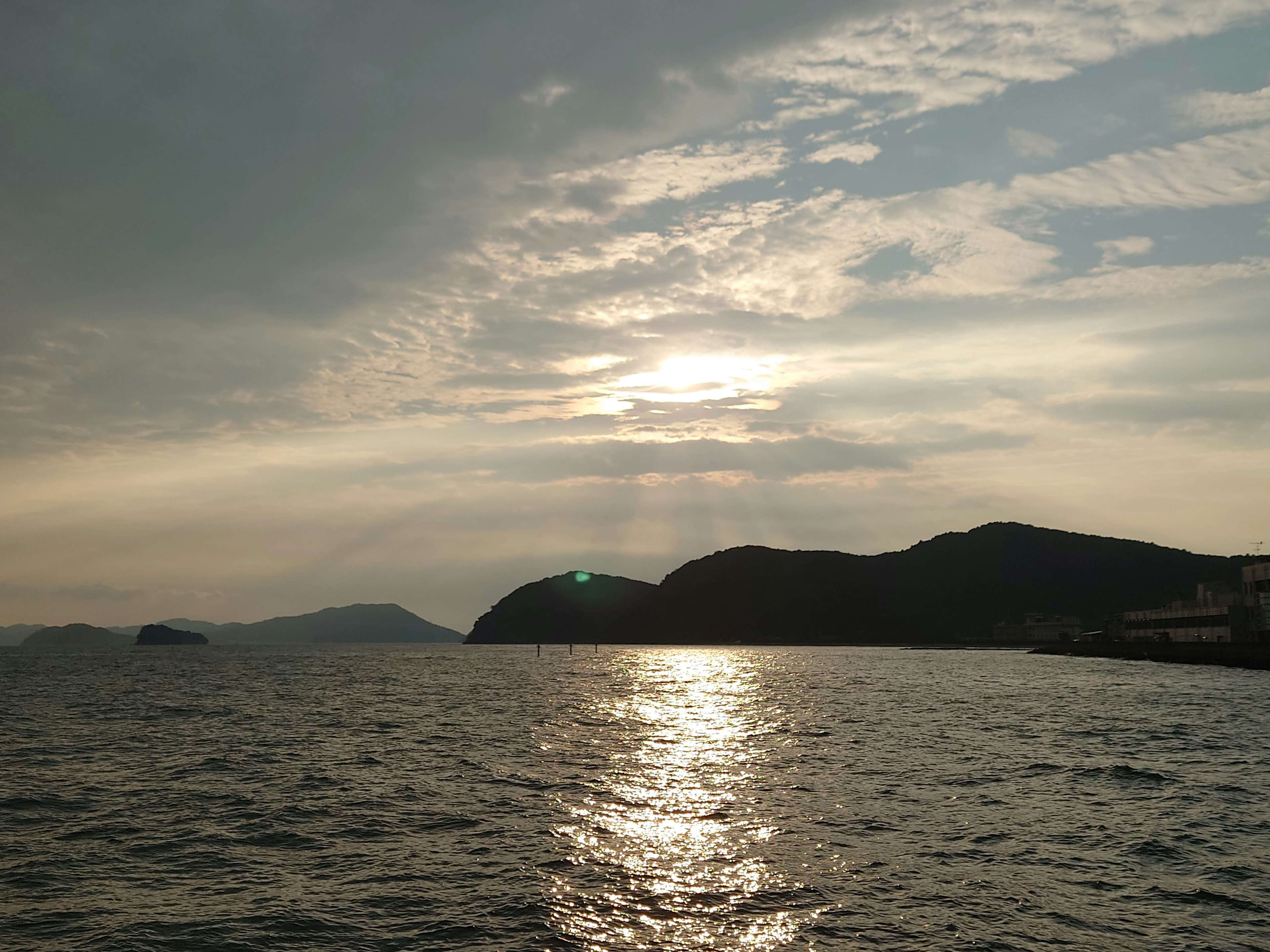 Atardecer sobre el agua con siluetas de montañas