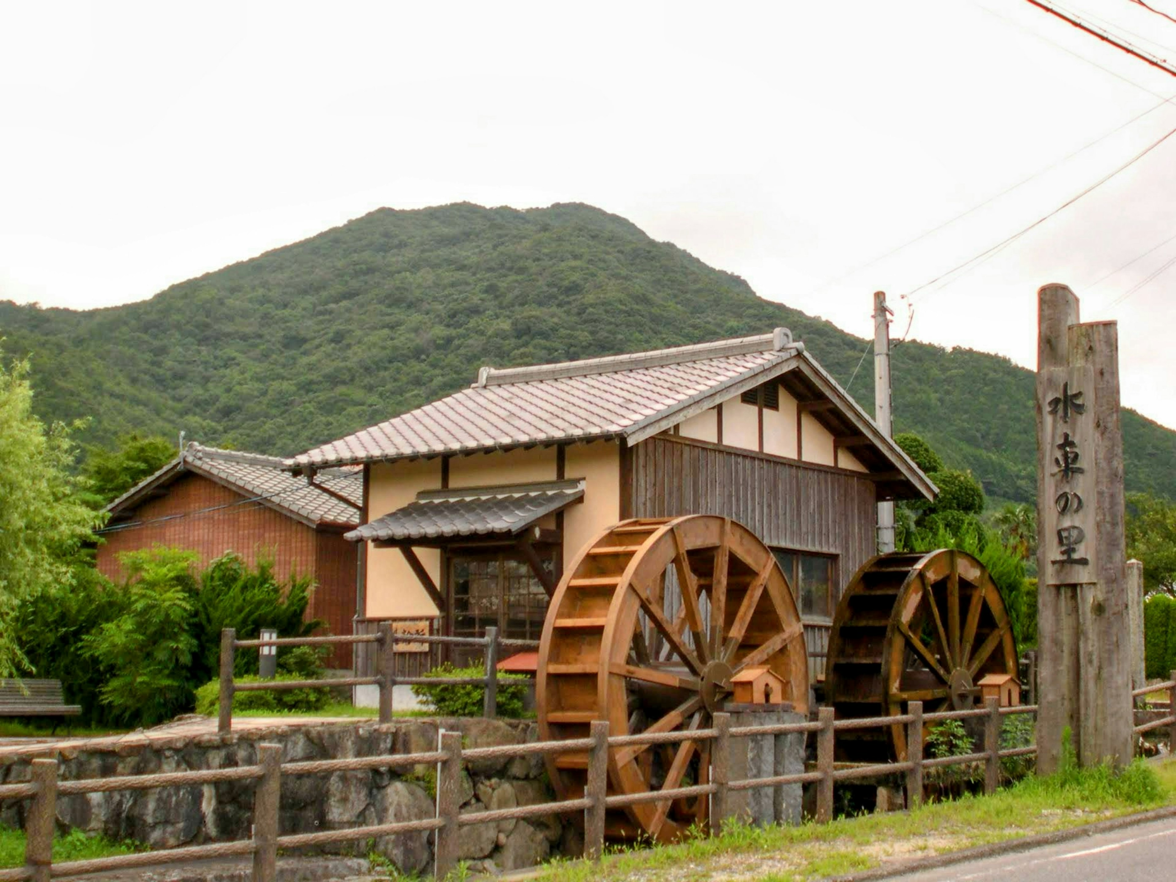 Edificio del mulino ad acqua con ruote di legno su sfondo montano