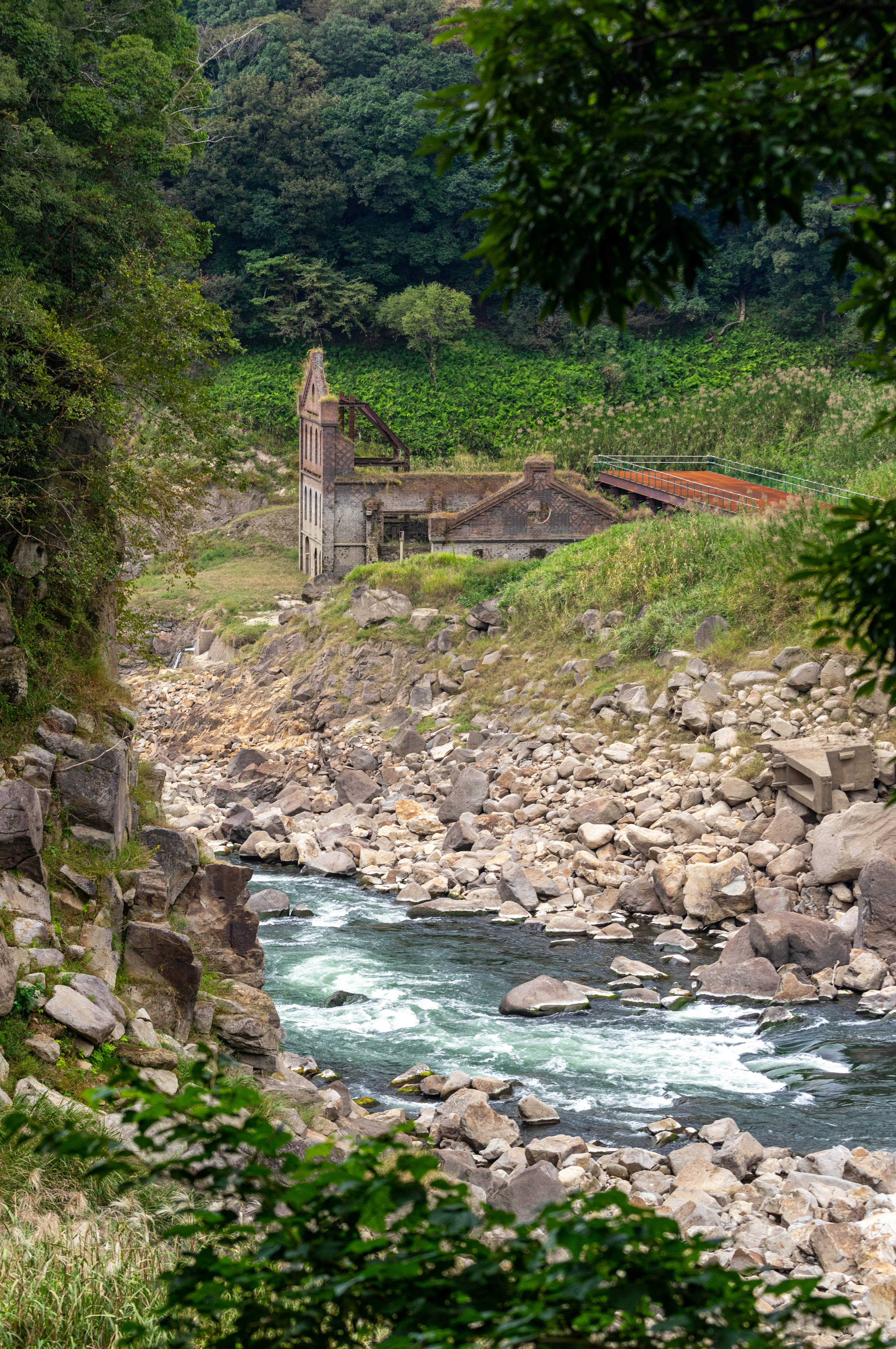 郁郁蔥蔥的山區中河邊的一座古老建築的風景