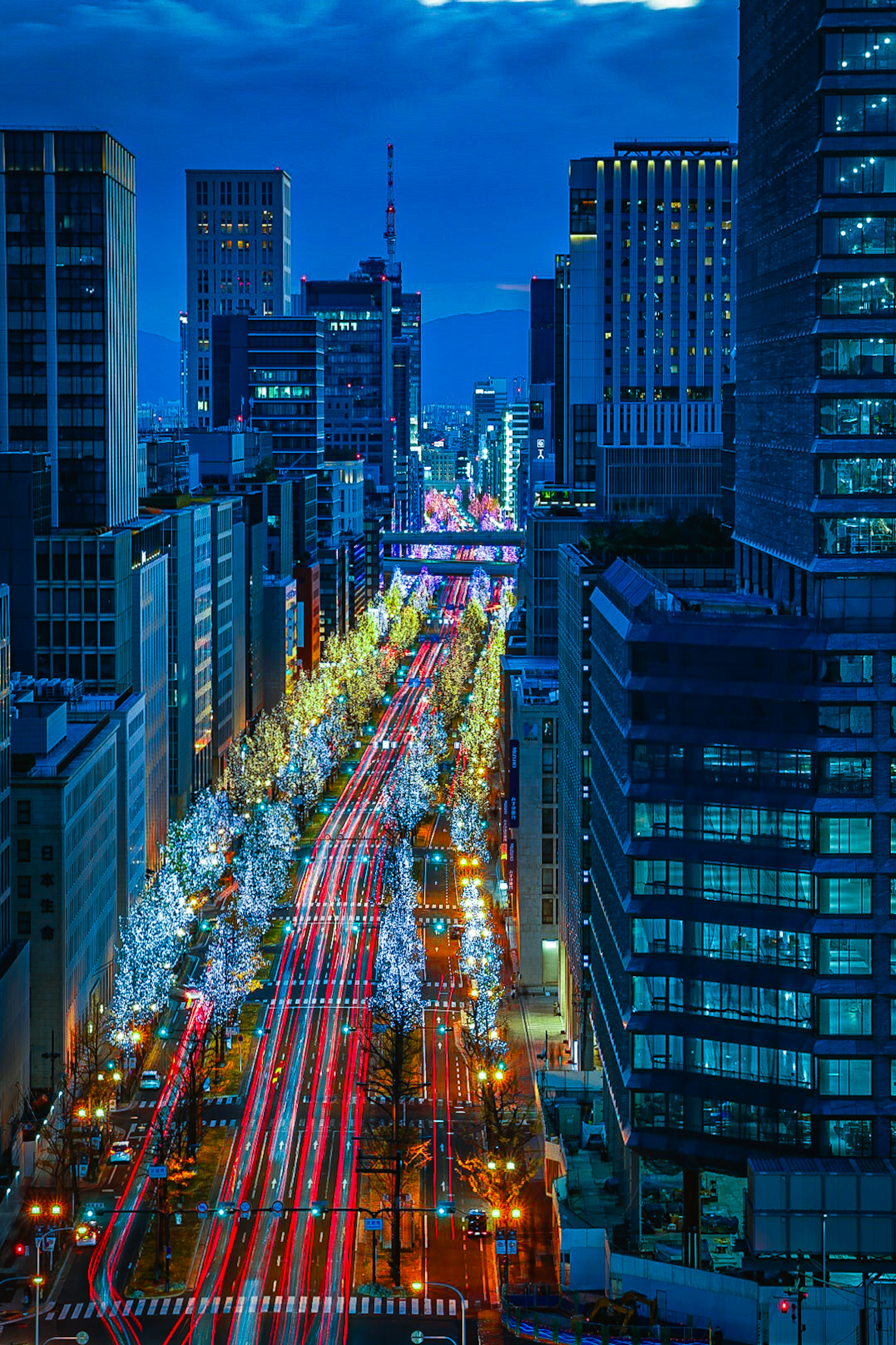 青い空の下の都会の夜景と光の軌跡