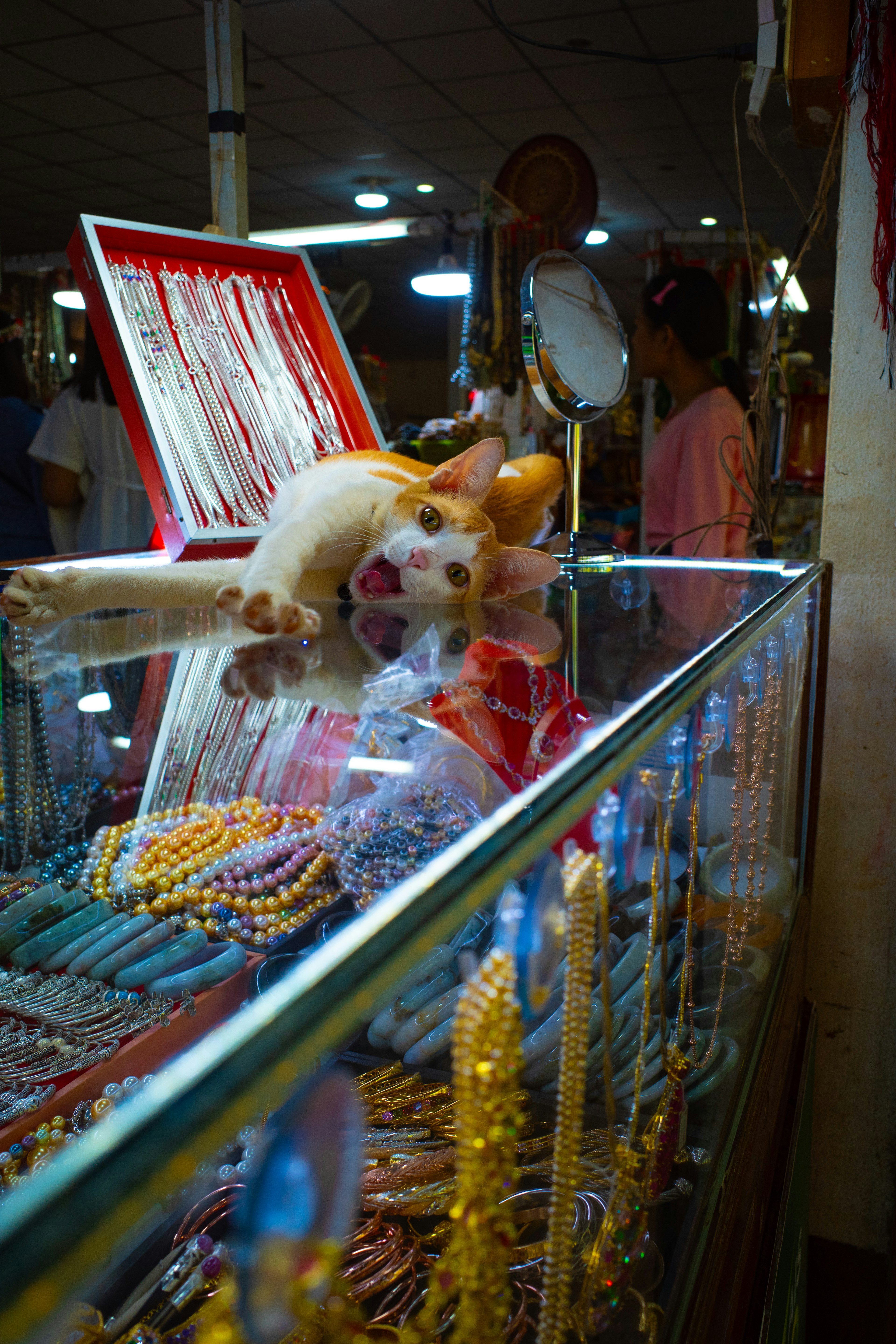 Artículos decorativos exhibidos en una vitrina de vidrio con personas al fondo en un mercado