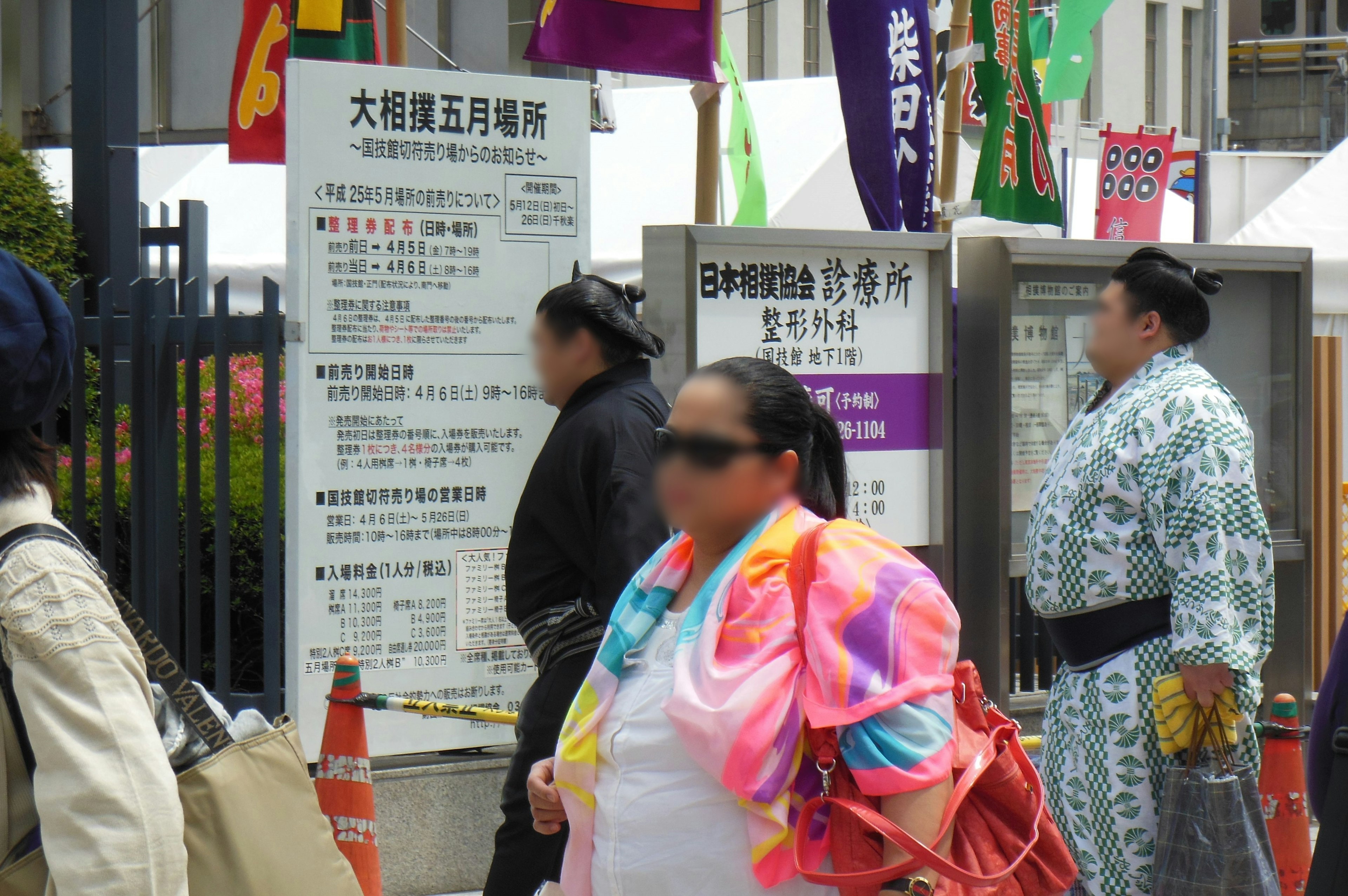 相撲会場の周辺にいる人々と看板