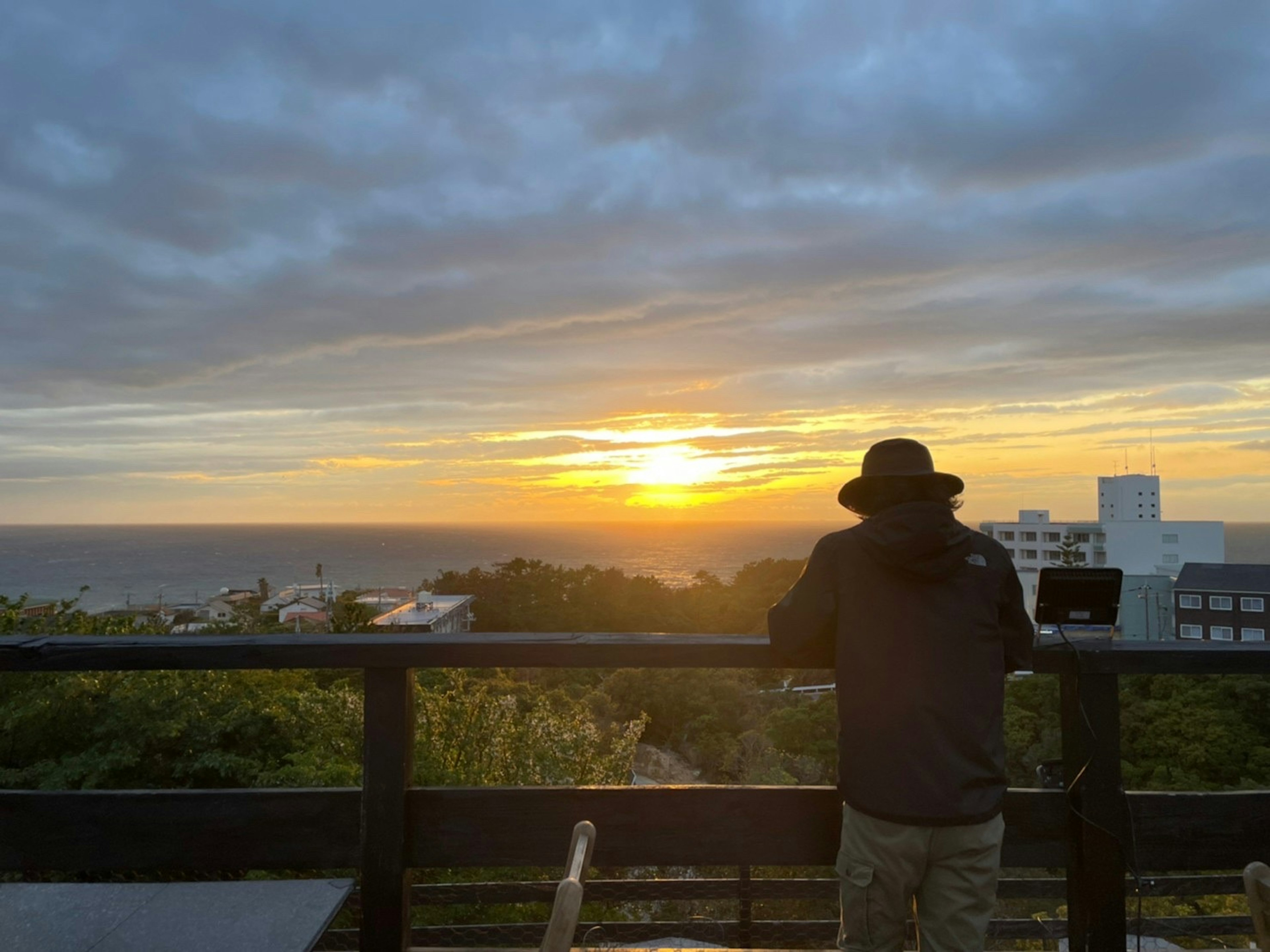 一个男人在看日落，背景是海洋和云朵