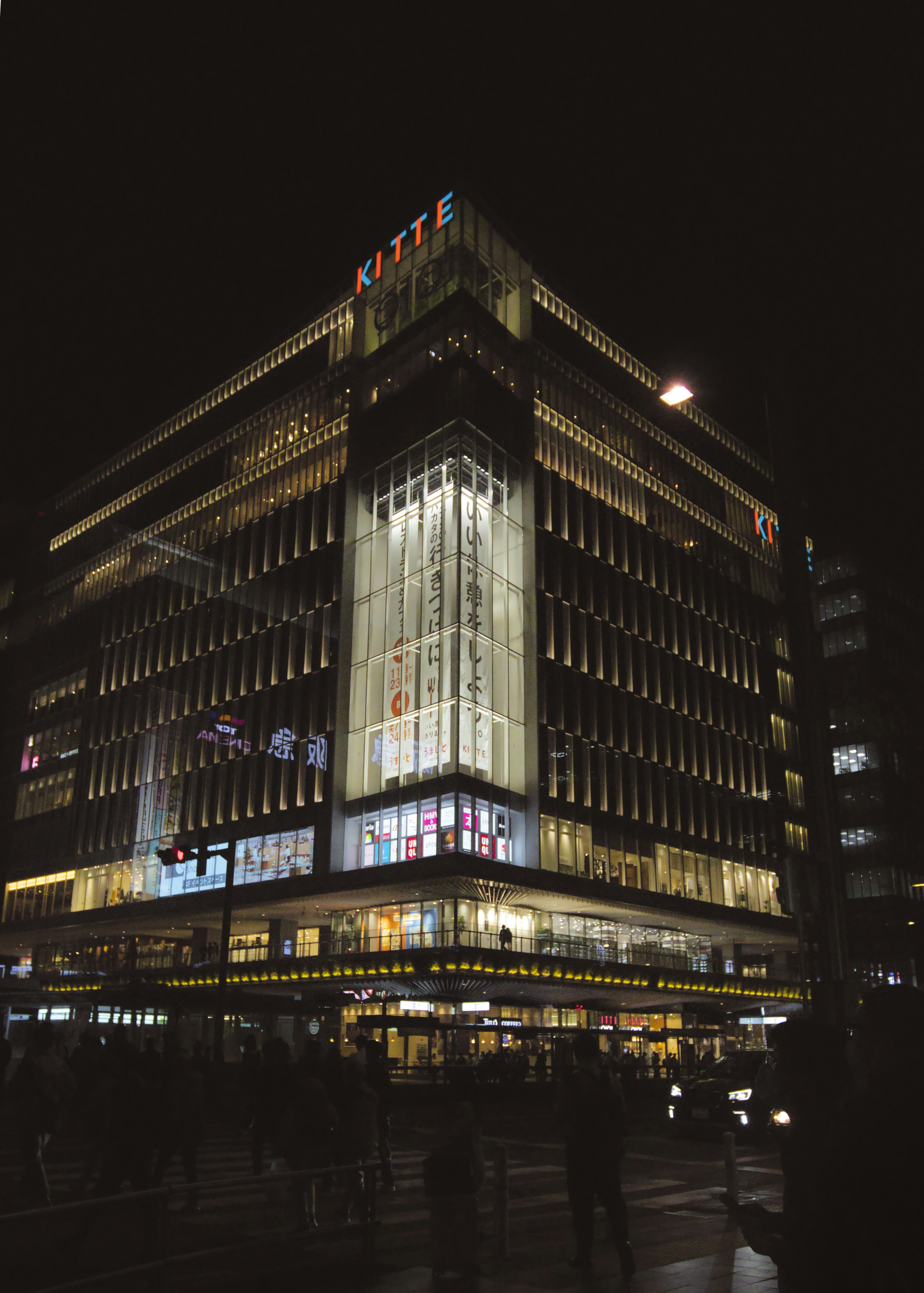 Modern building facade illuminated at night with bright windows and signage