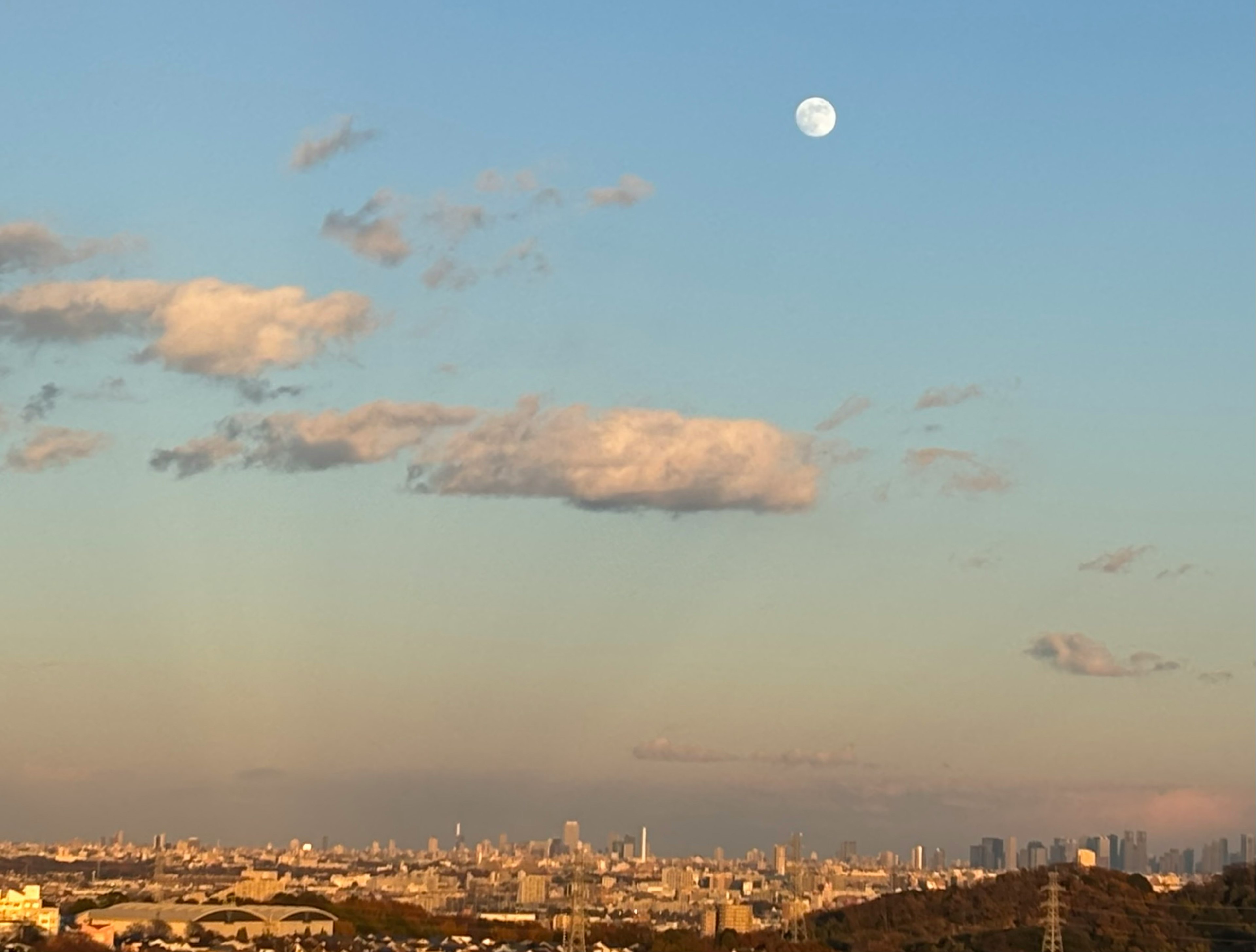 Paesaggio urbano con cielo sereno e luna visibile tra le nuvole