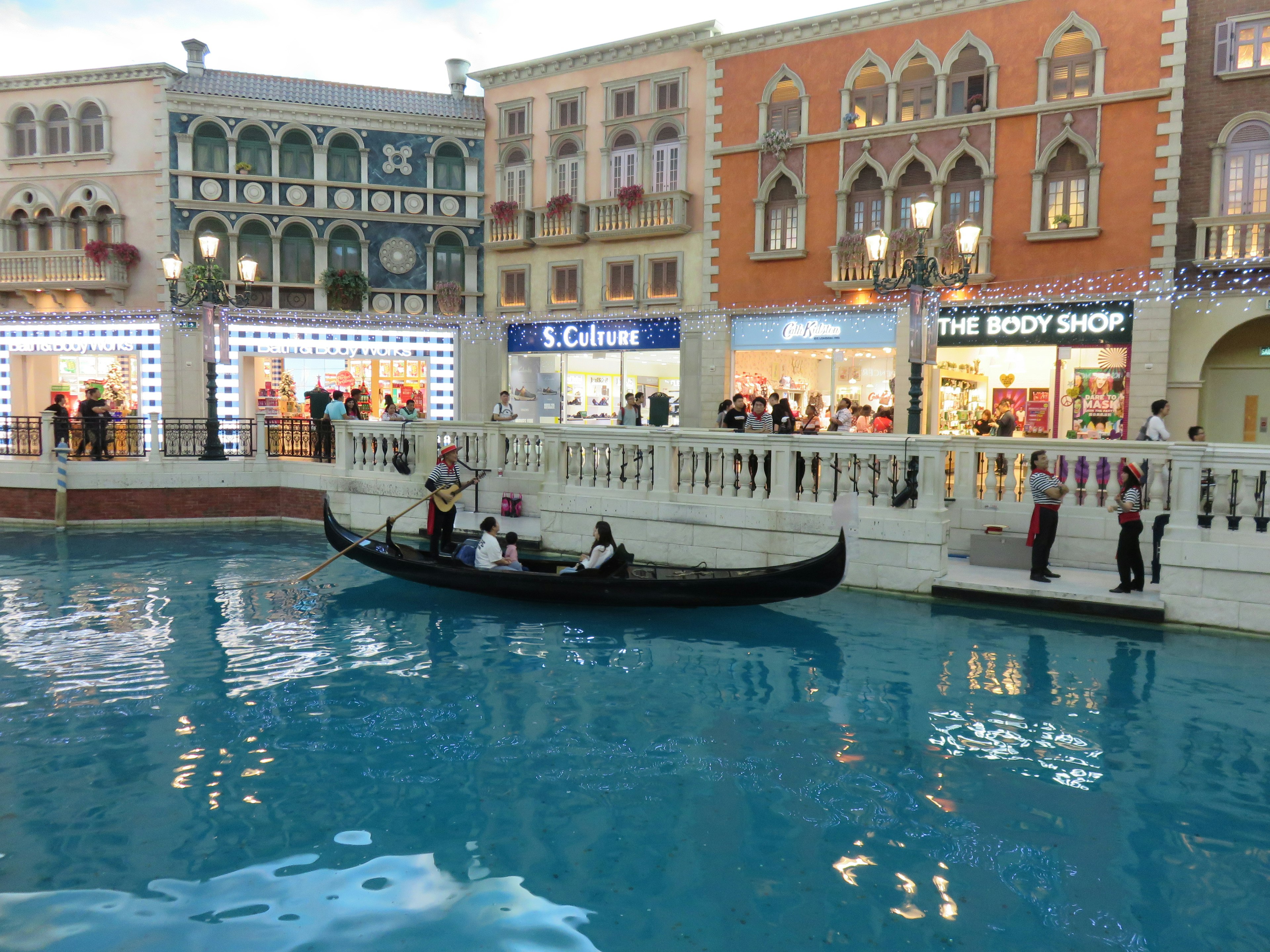 Gondola yang berlayar di kanal dengan bangunan toko yang indah