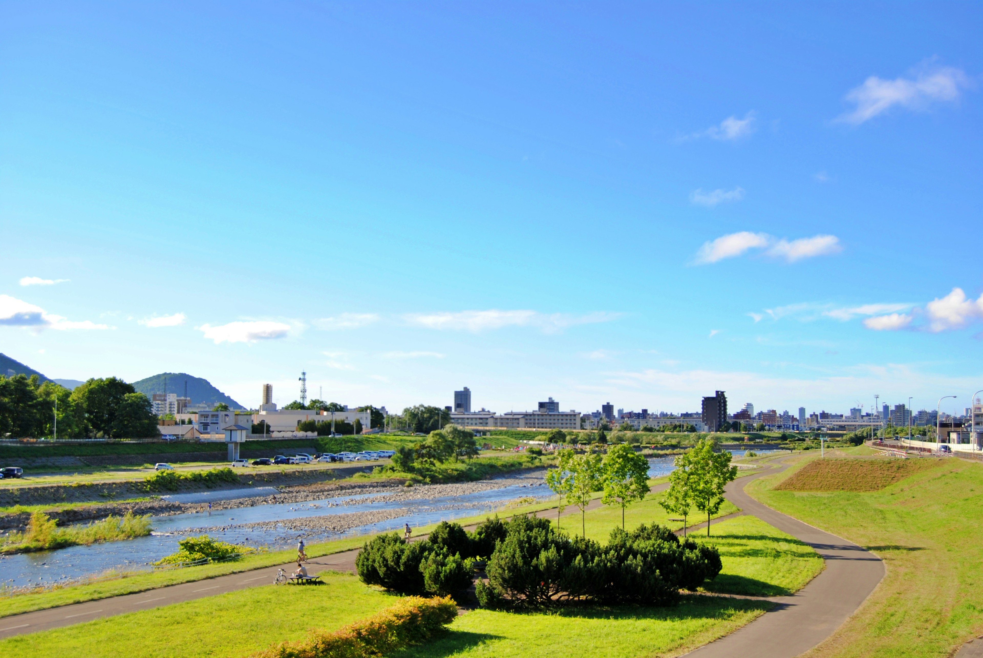 Rivière sous un ciel bleu avec verdure et skyline de la ville au loin