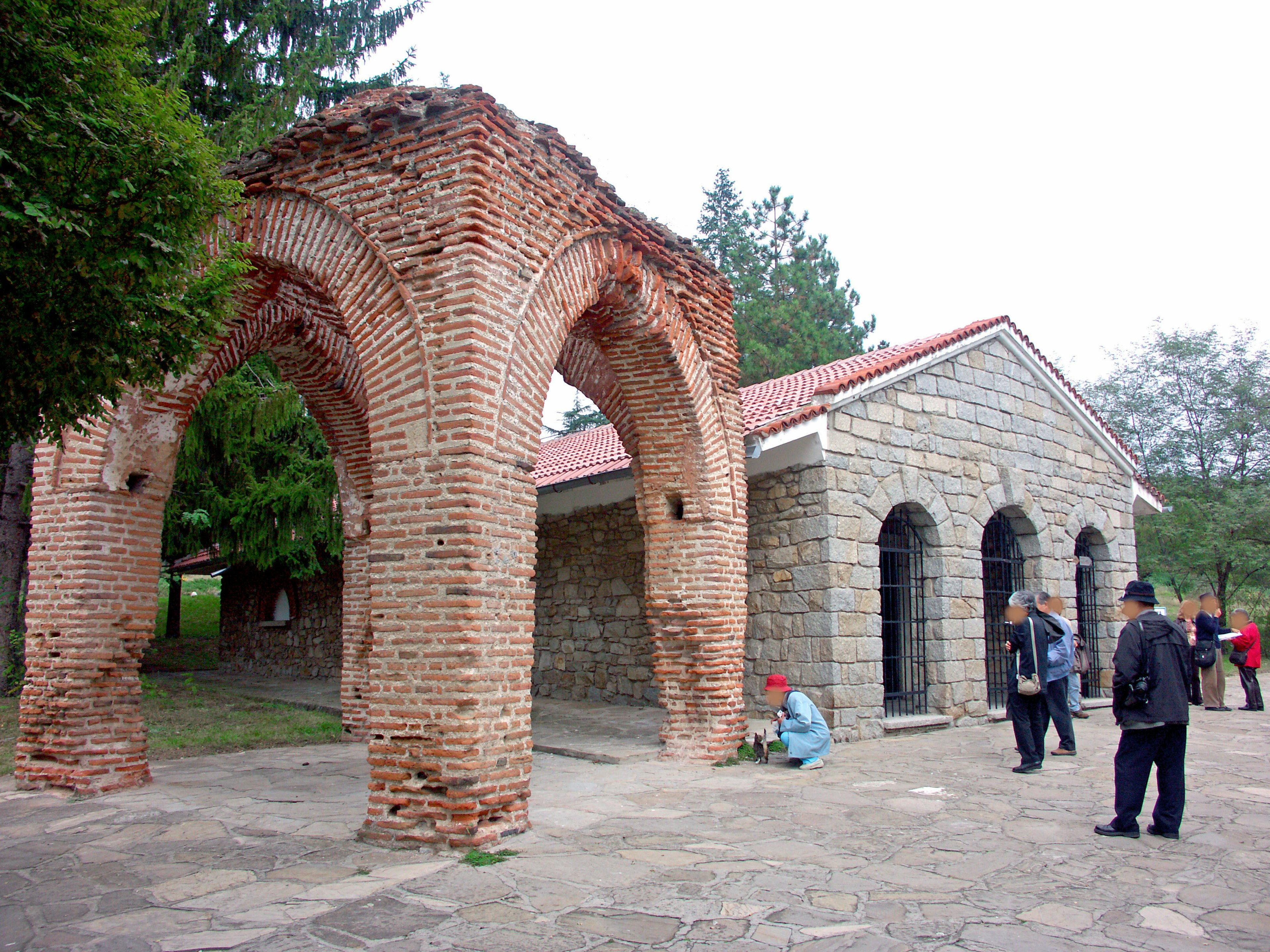 Antiguo arco de ladrillos con un edificio de piedra al fondo