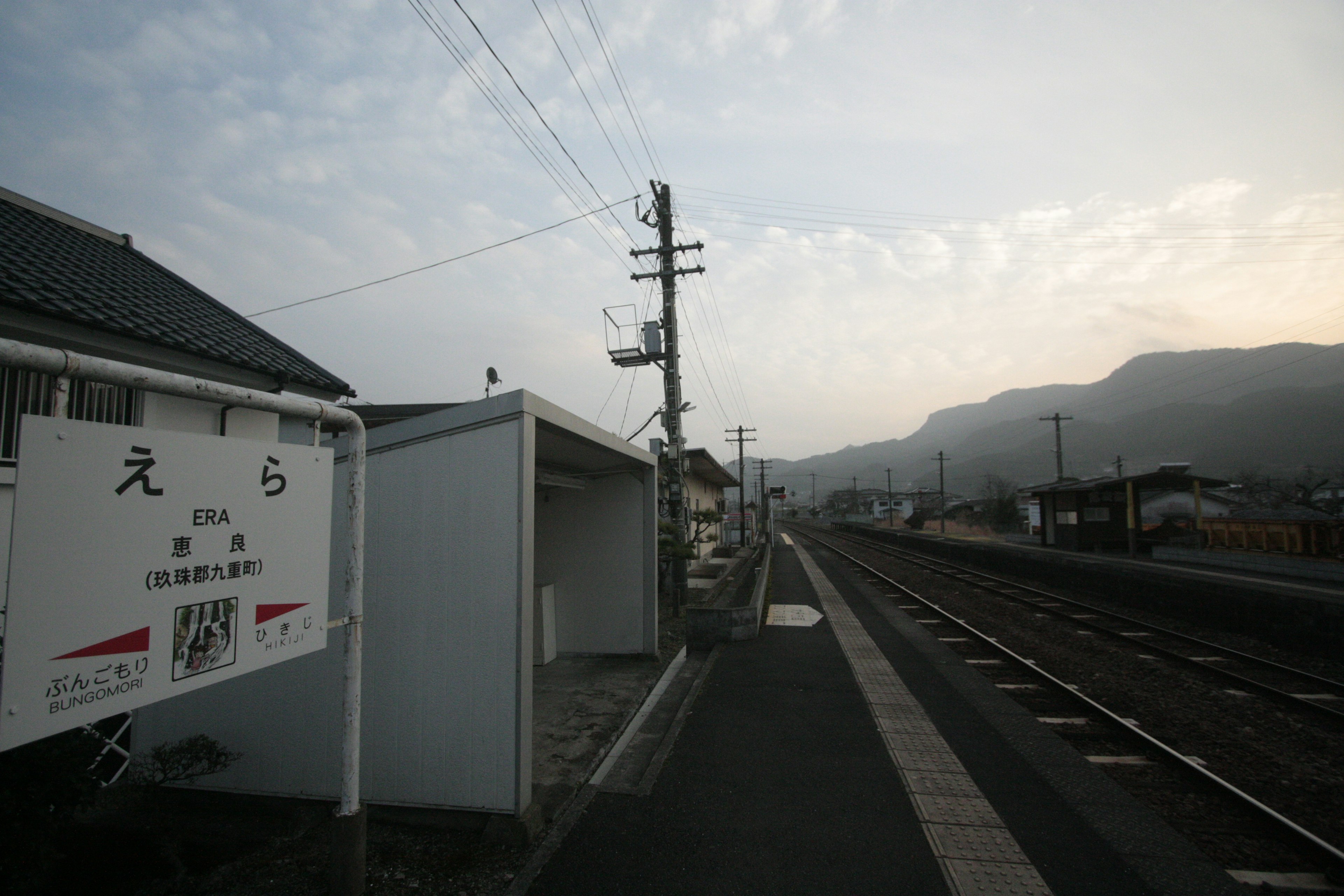 Ruhige Bahnhofszenen mit Bergen und Farbverlauf des Himmels mit Bahn und Stationsschild