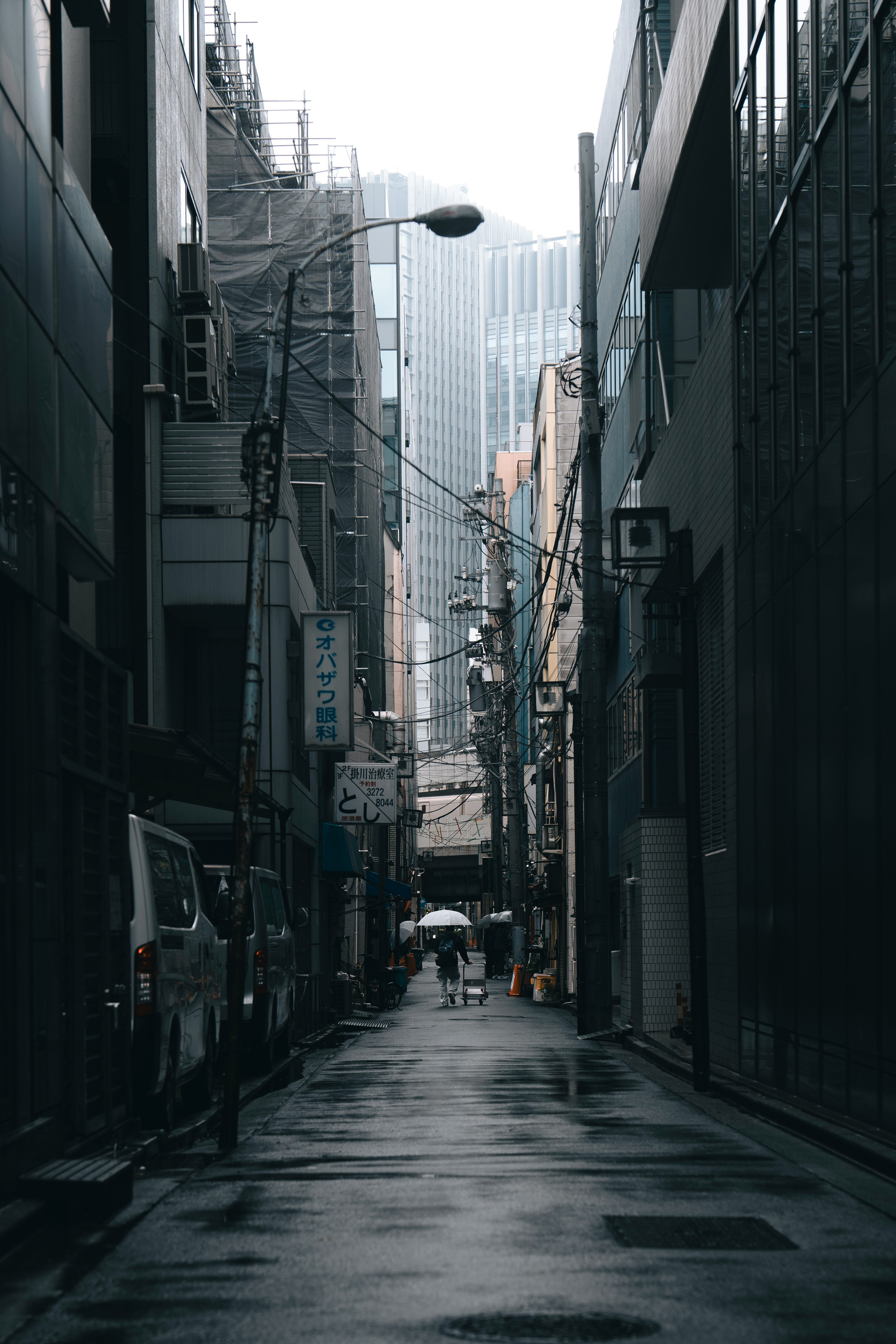 Quiet urban alley in the rain surrounded by buildings narrow street with reflective wet pavement