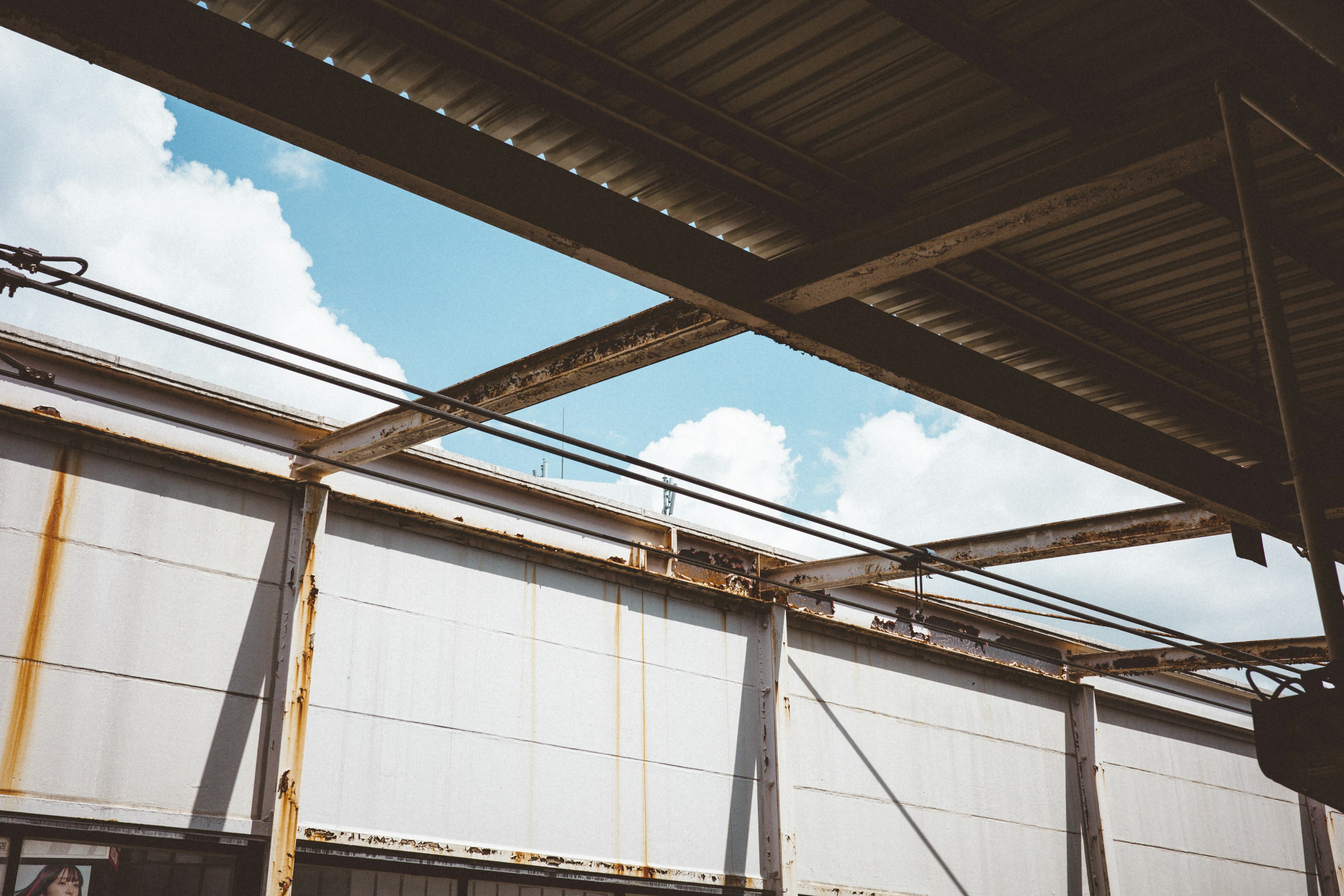 View of blue sky and white clouds through industrial roof structure