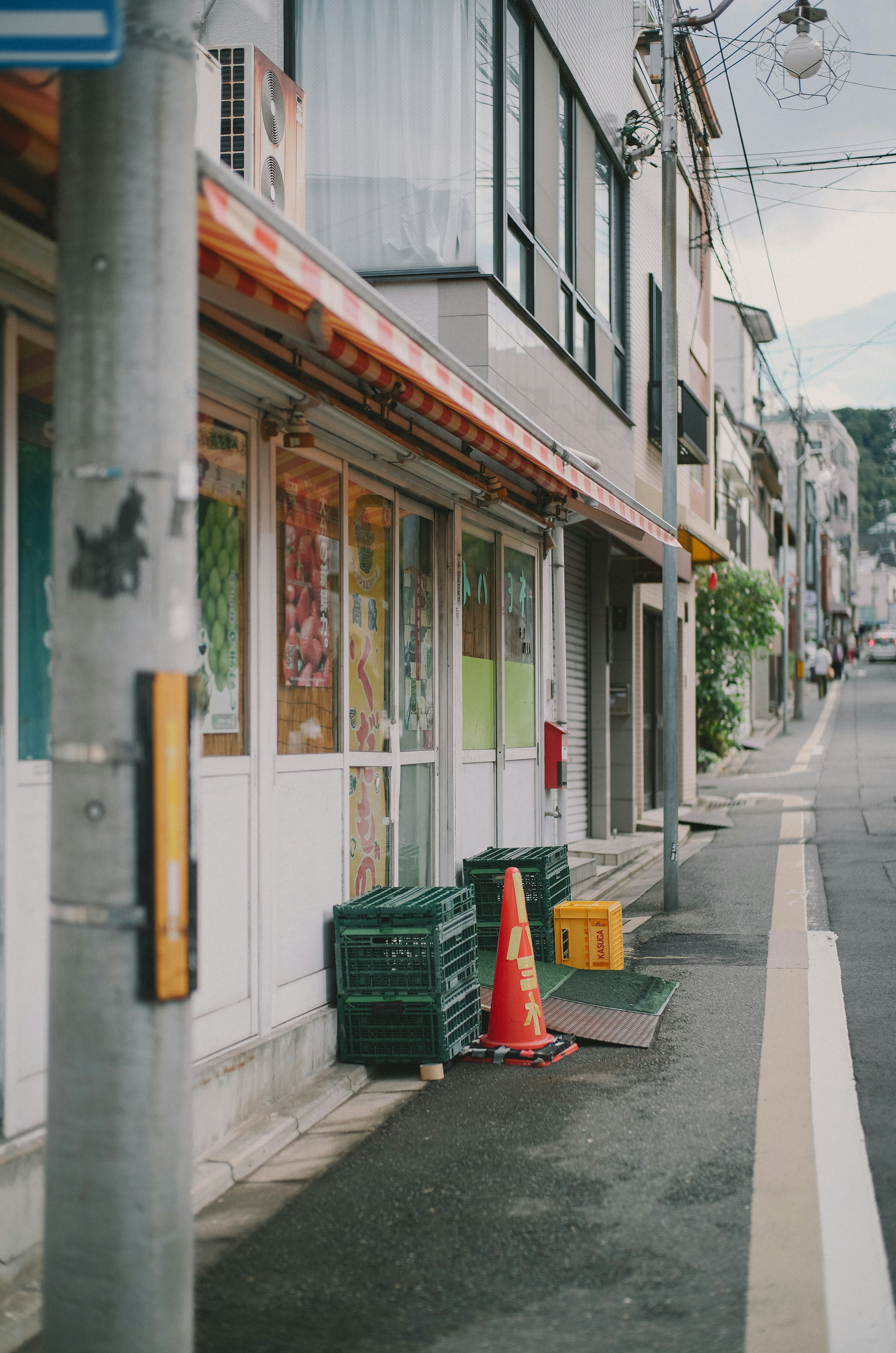 Street view featuring storefronts and a traffic cone