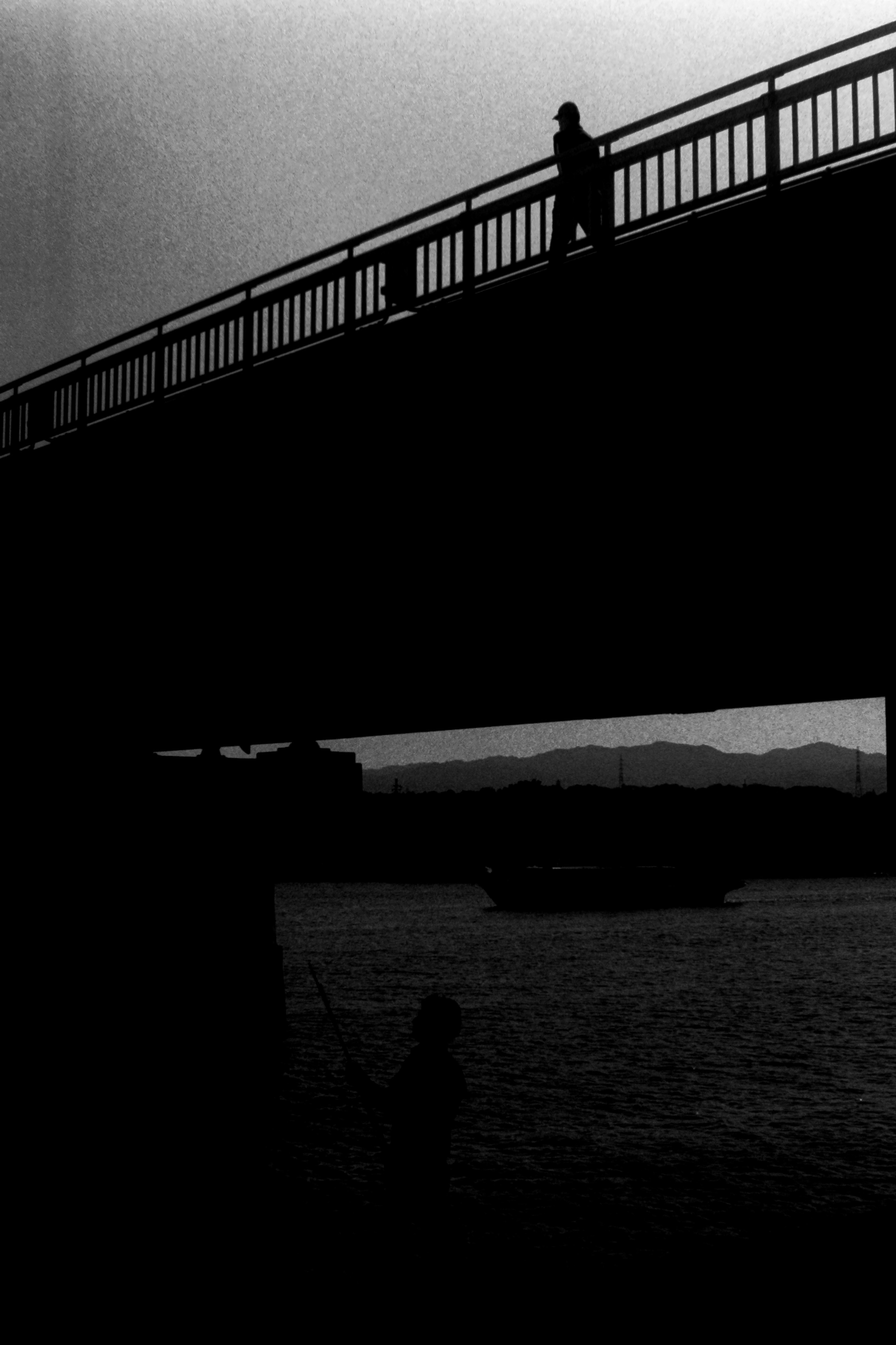 Silueta de una persona caminando sobre un puente con reflejos en el agua