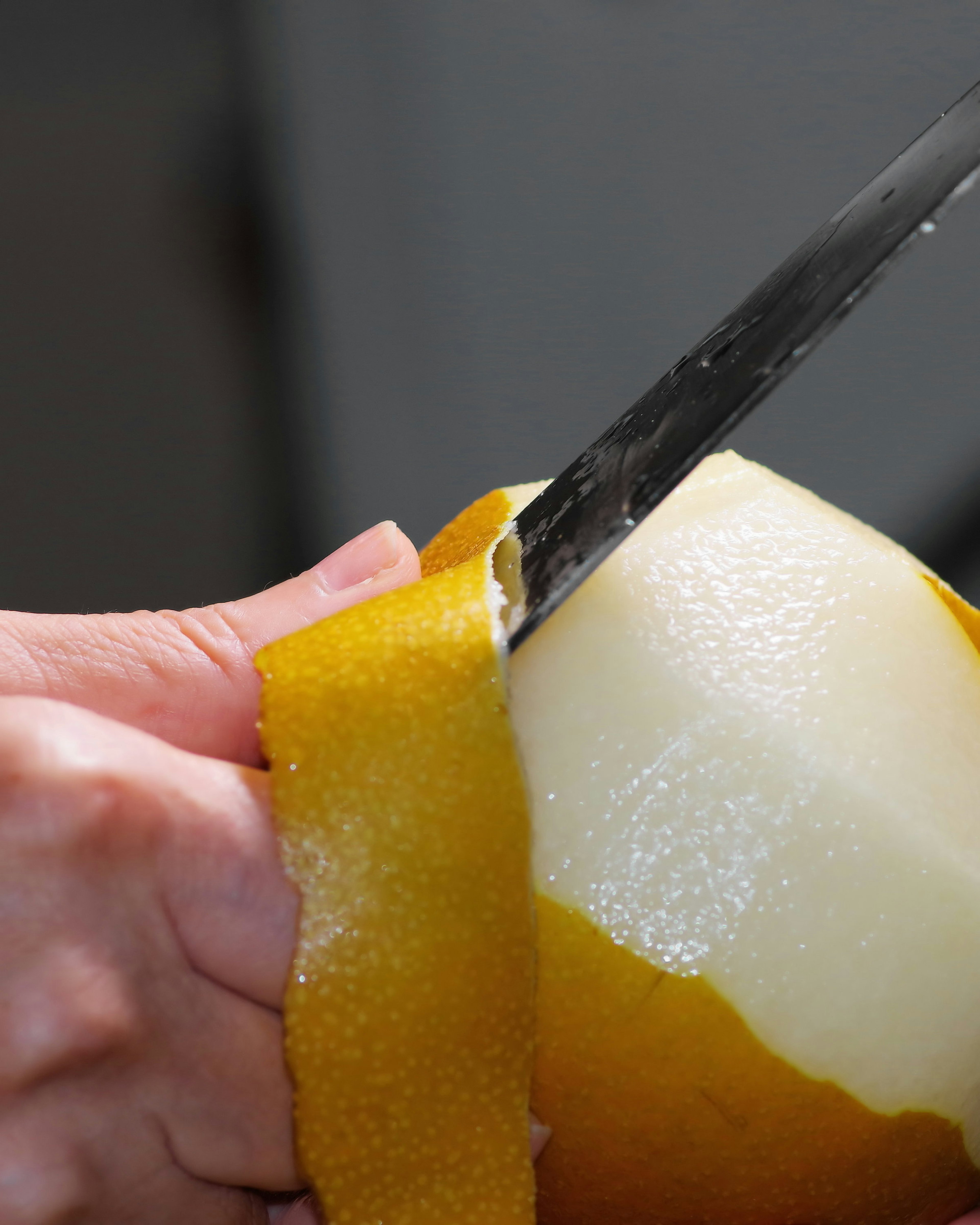 Image of a person peeling a pear with a knife