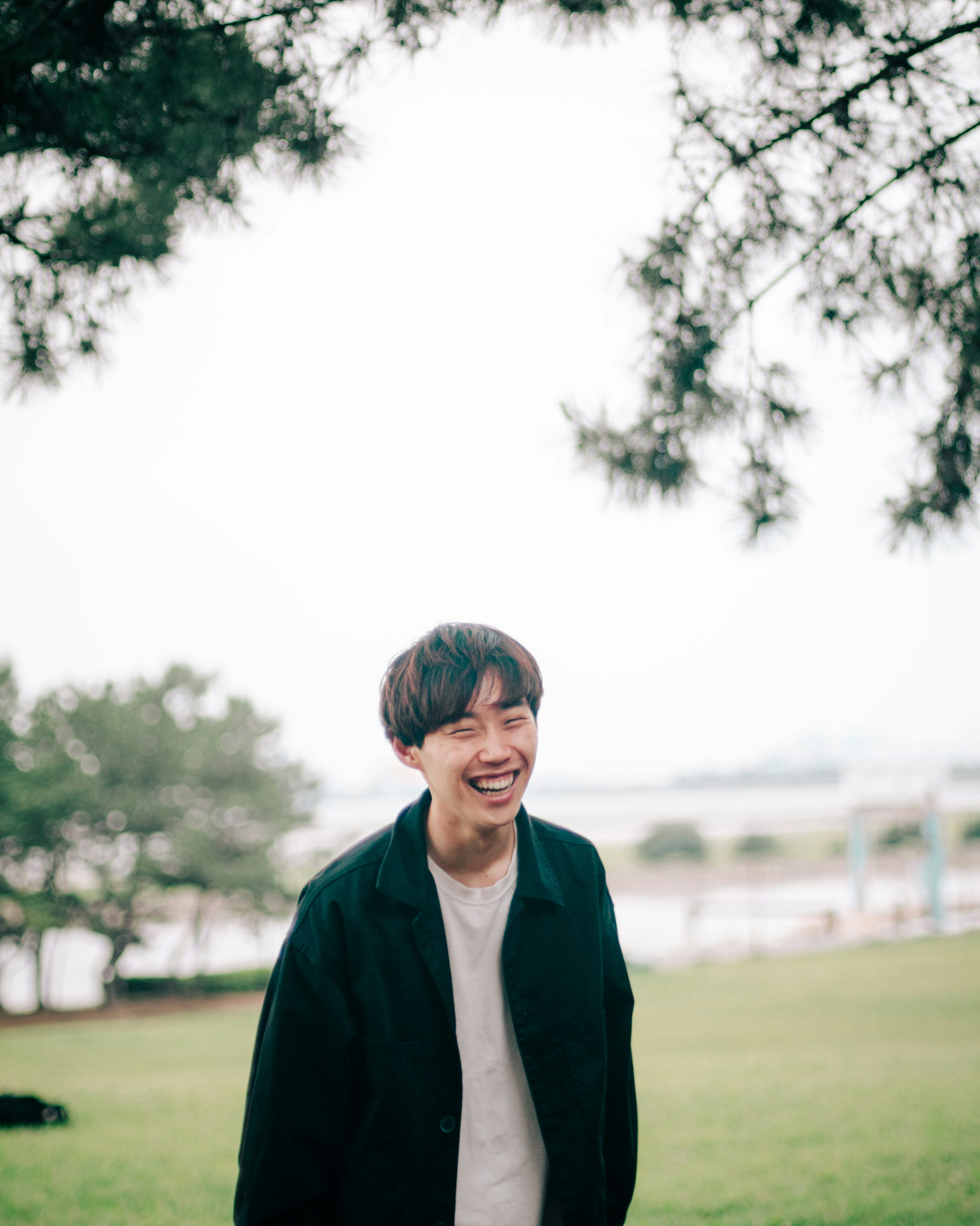 Smiling man in a park with green grass and trees in the background