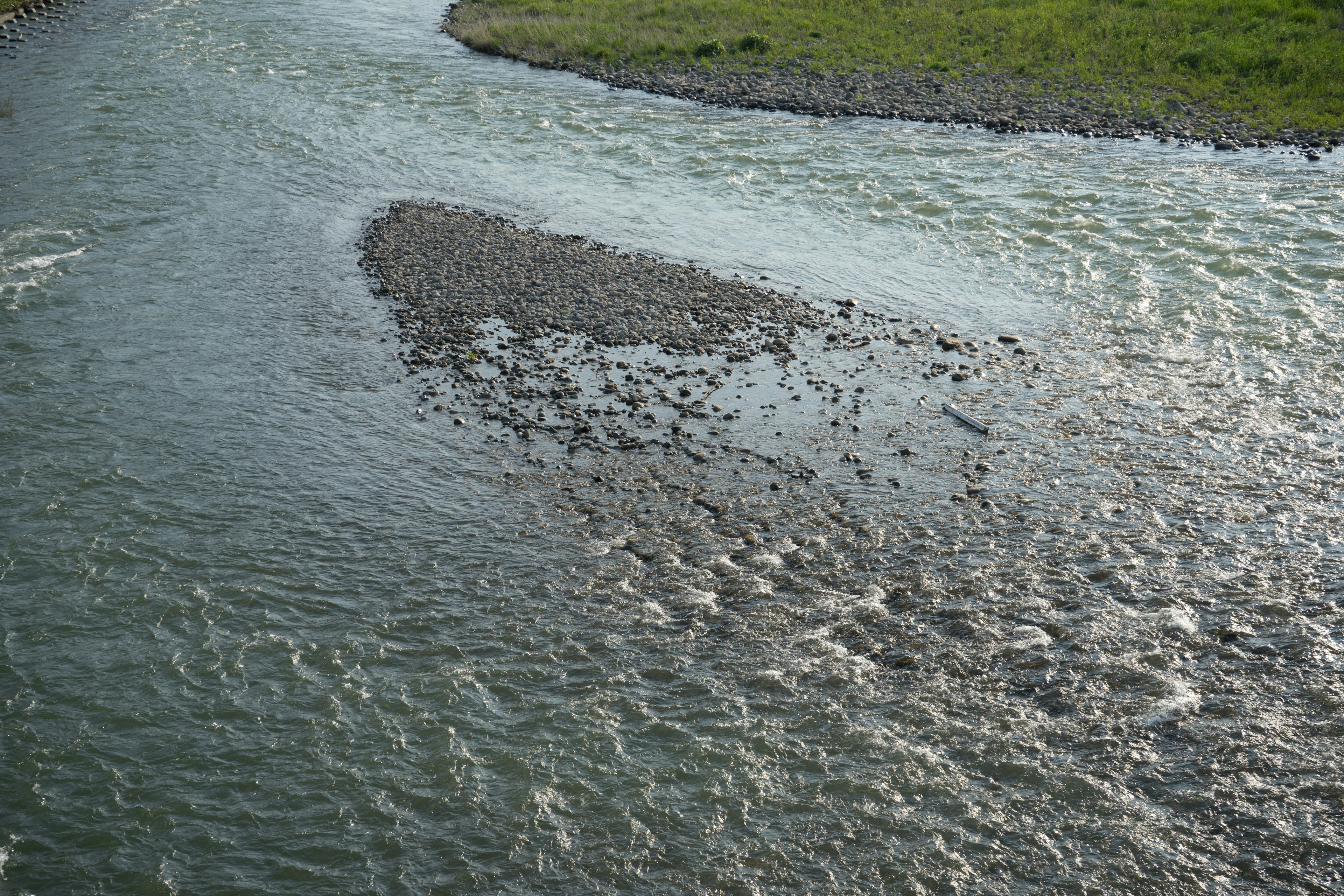 Paysage de rivière avec de l'eau en mouvement et une île de gravier