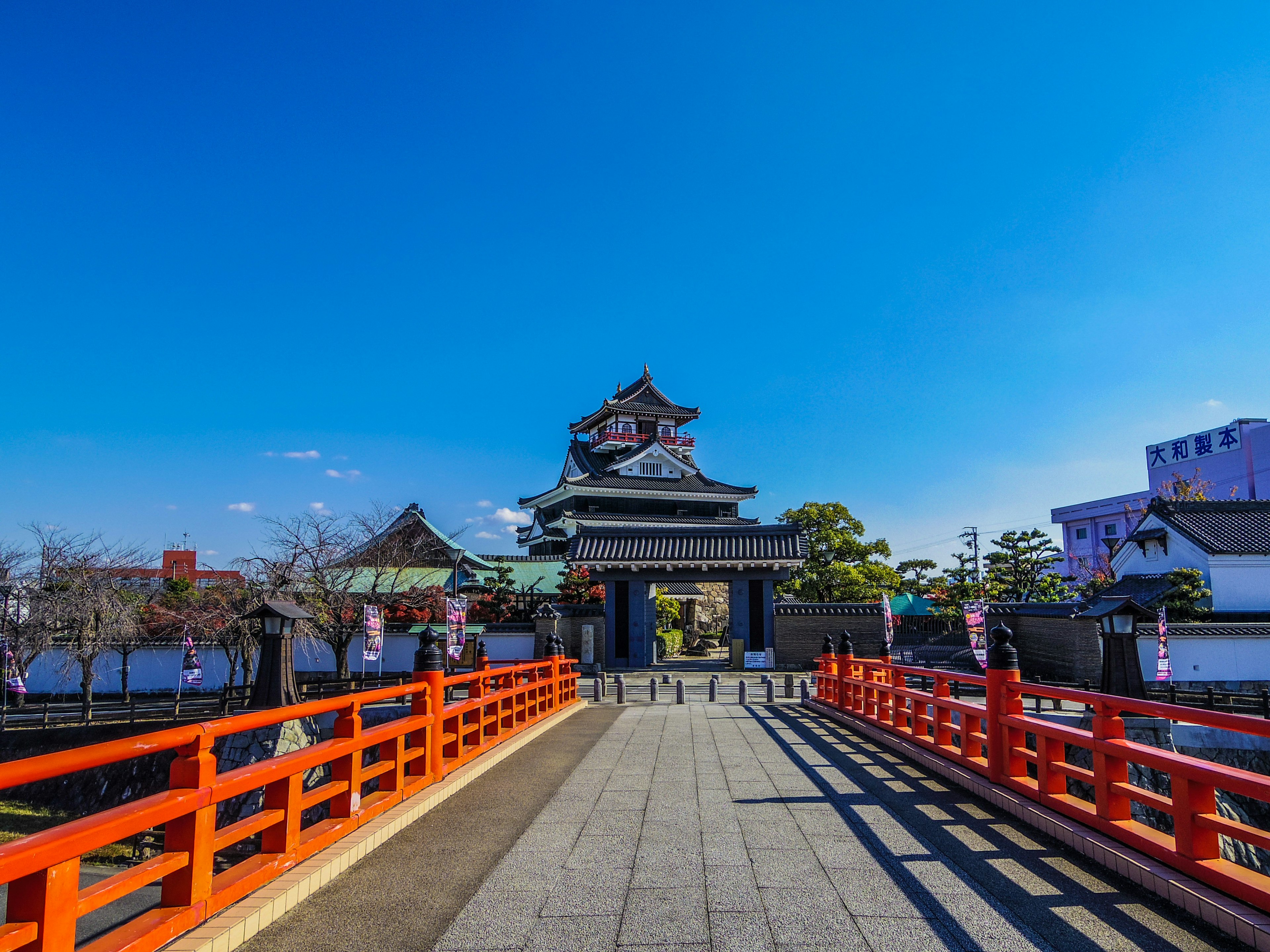 Kastil Jepang tradisional di bawah langit biru dengan jembatan merah