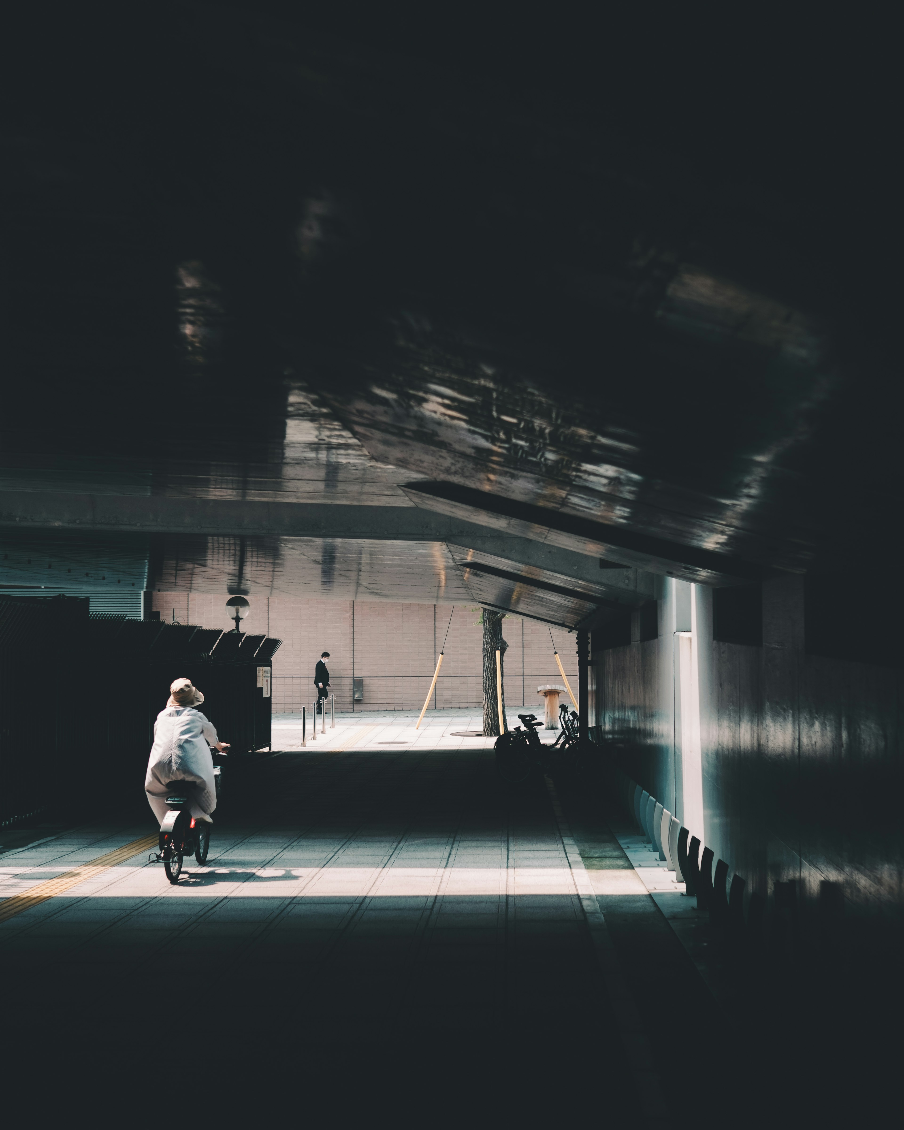 Silhouette di una persona che cammina in un tunnel poco illuminato con contrasto di luce