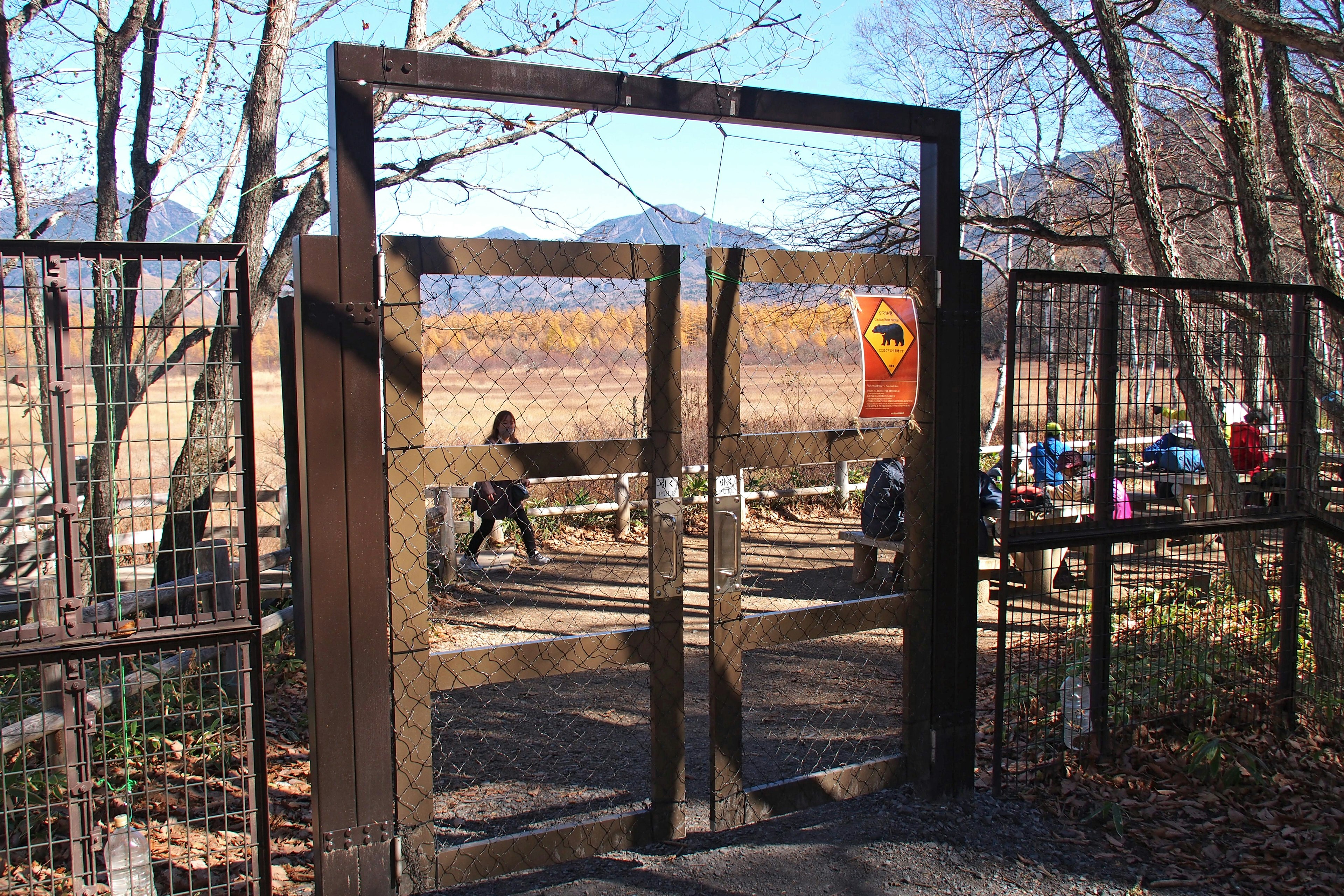 Puerta de madera que conduce a un paisaje natural con personas