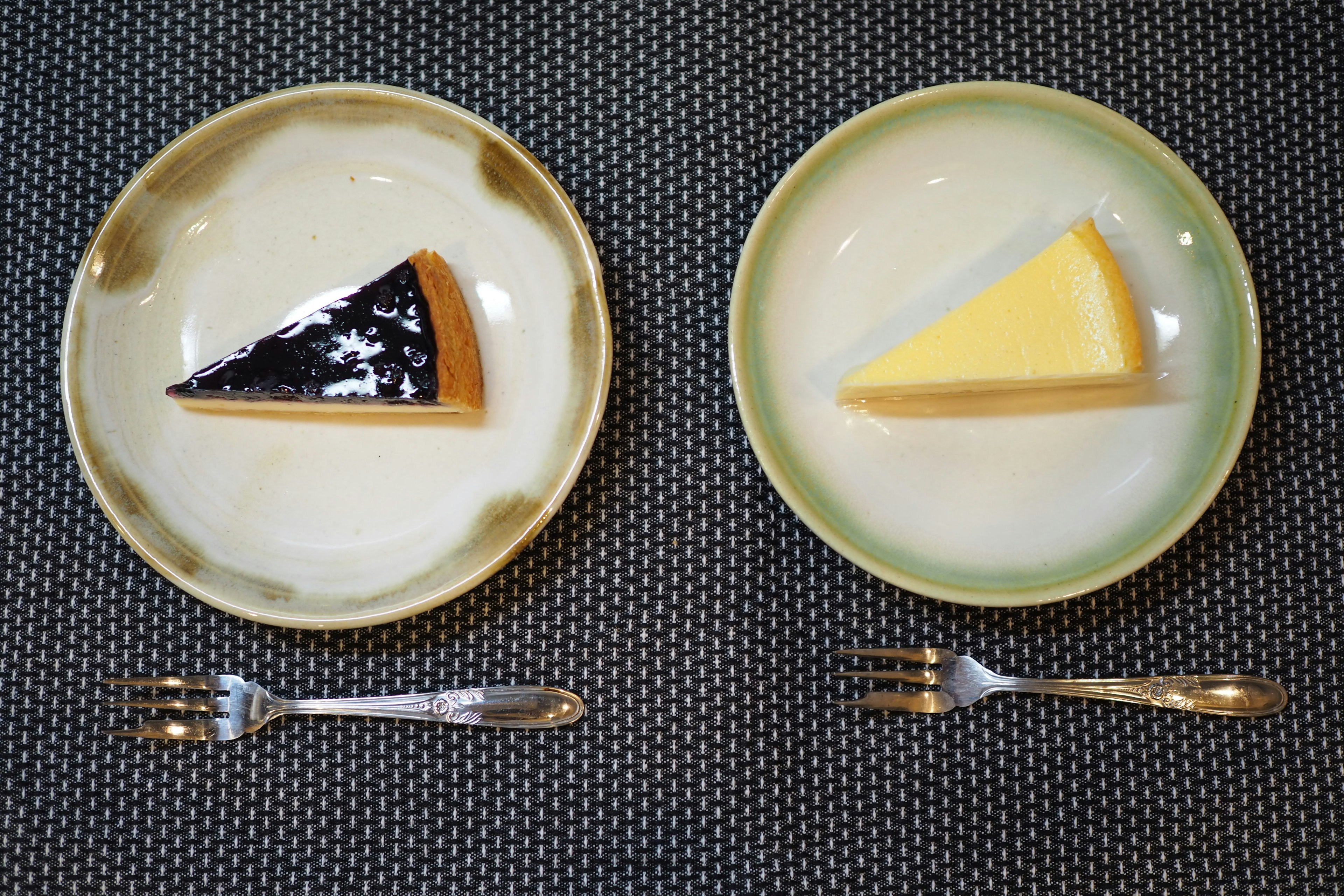 Two plates with a slice of black cake and a slice of yellow cake