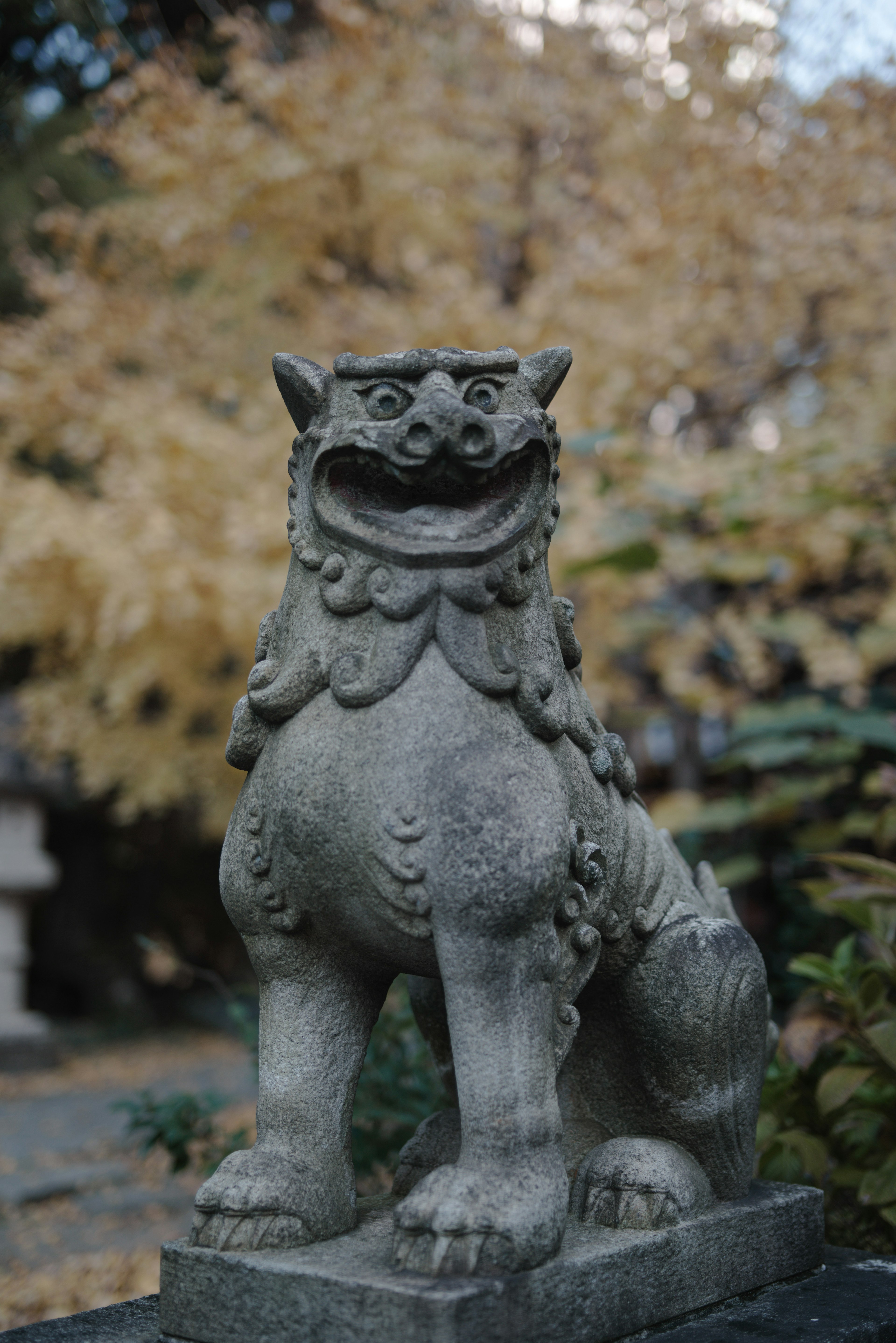 Estatua de león de piedra de pie entre el follaje otoñal