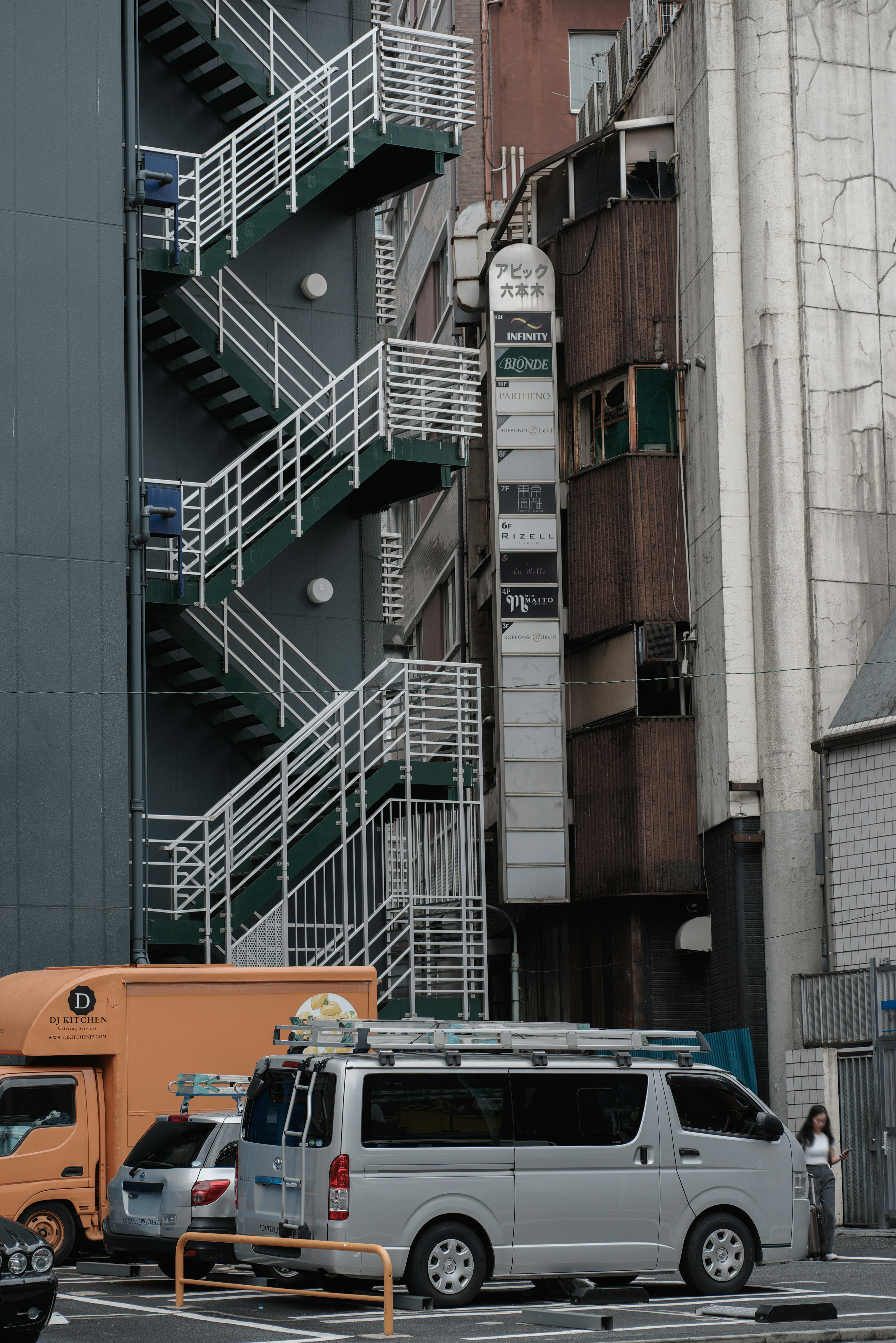 Narrow alley featuring a white fire escape and adjacent narrow building exterior