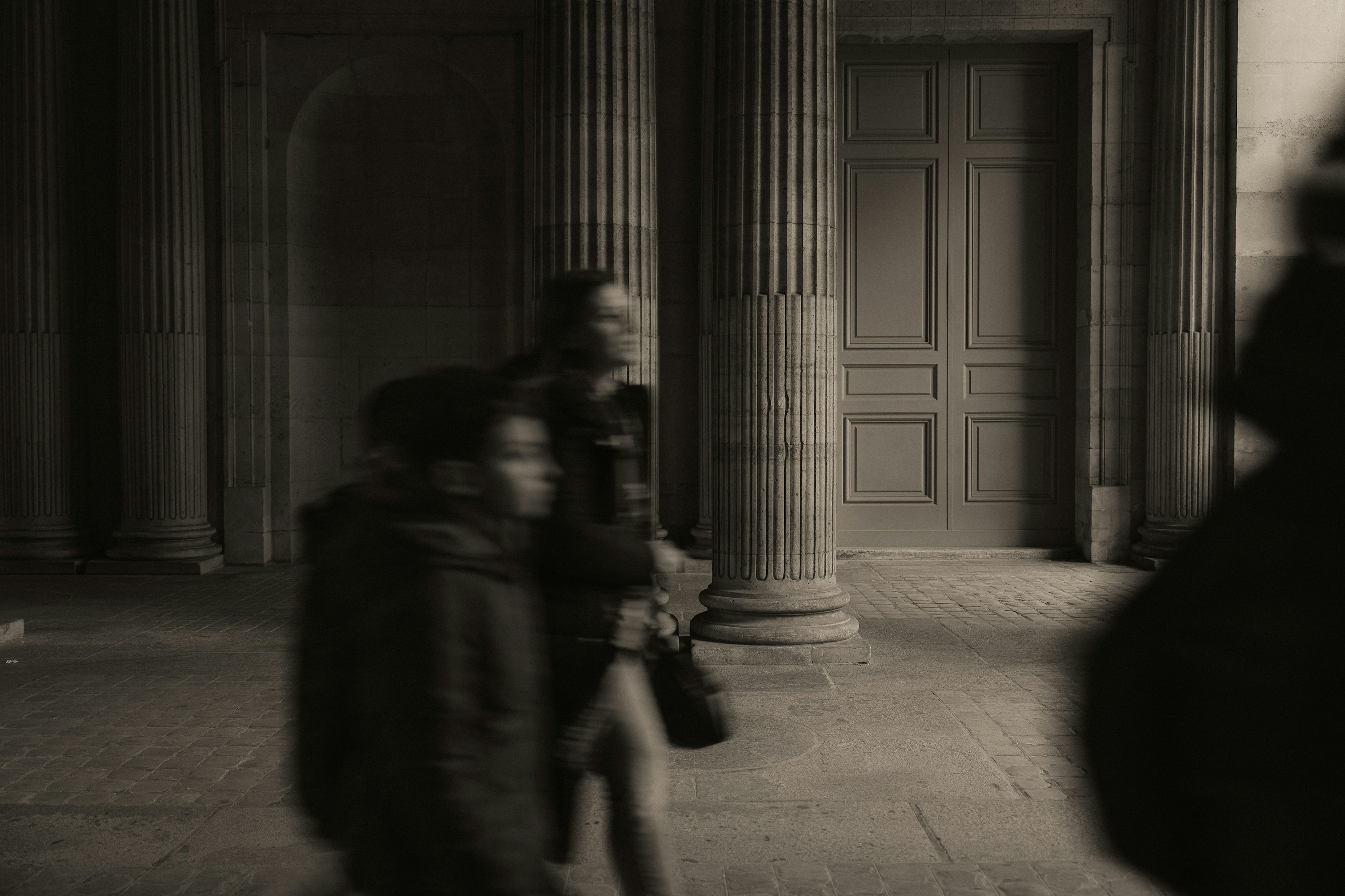 Photo en noir et blanc de personnes marchant dans l'intérieur d'un bâtiment historique