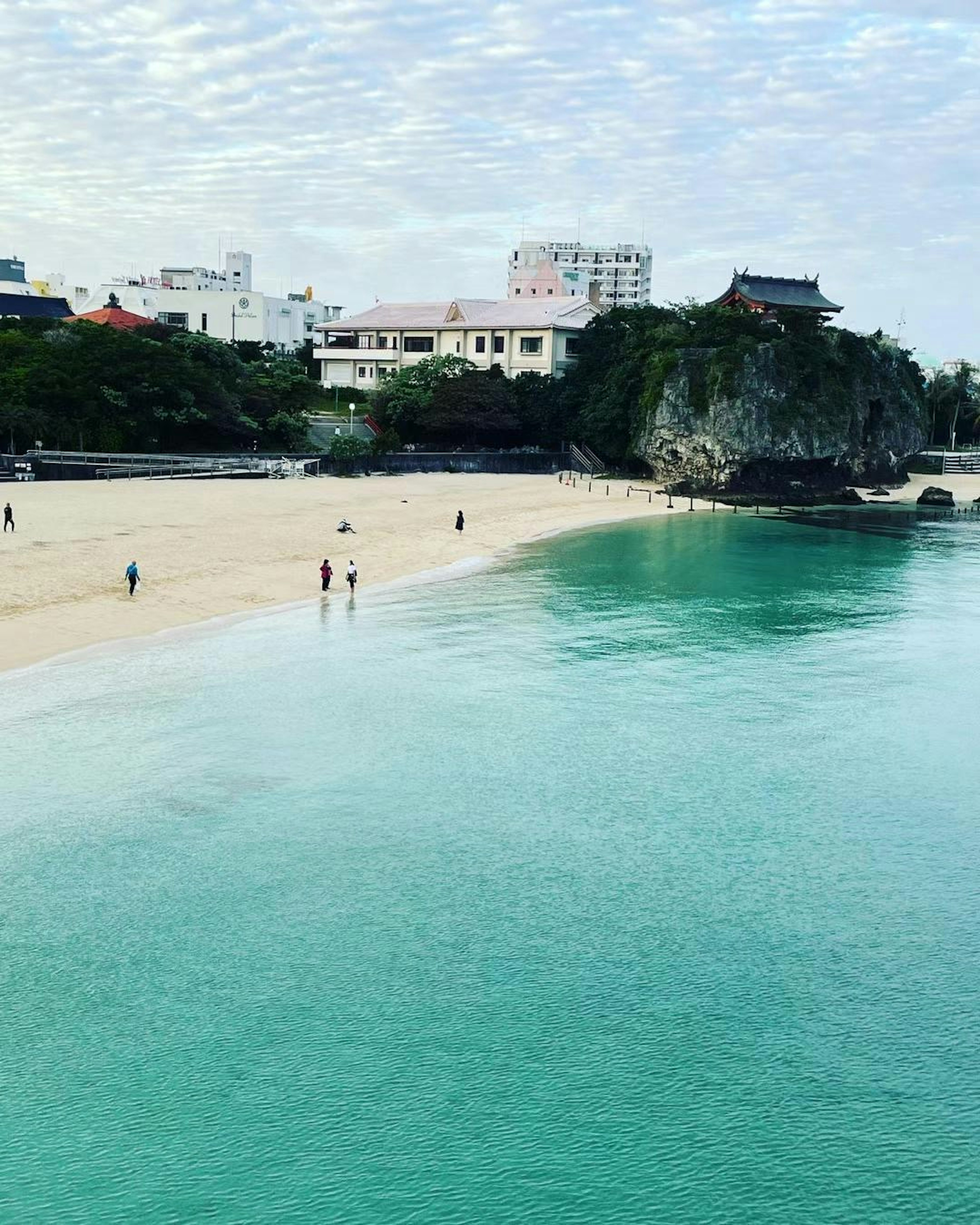 Plage avec eau turquoise et sable blanc avec des gens marchant