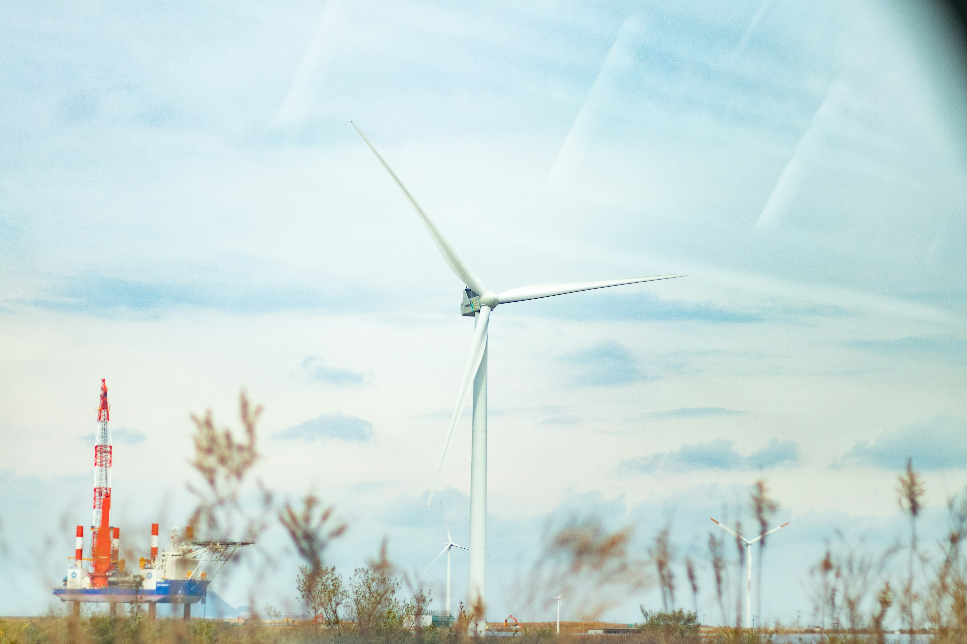 Windkraftanlage und rot-weißer Kommunikationsturm in der Landschaft