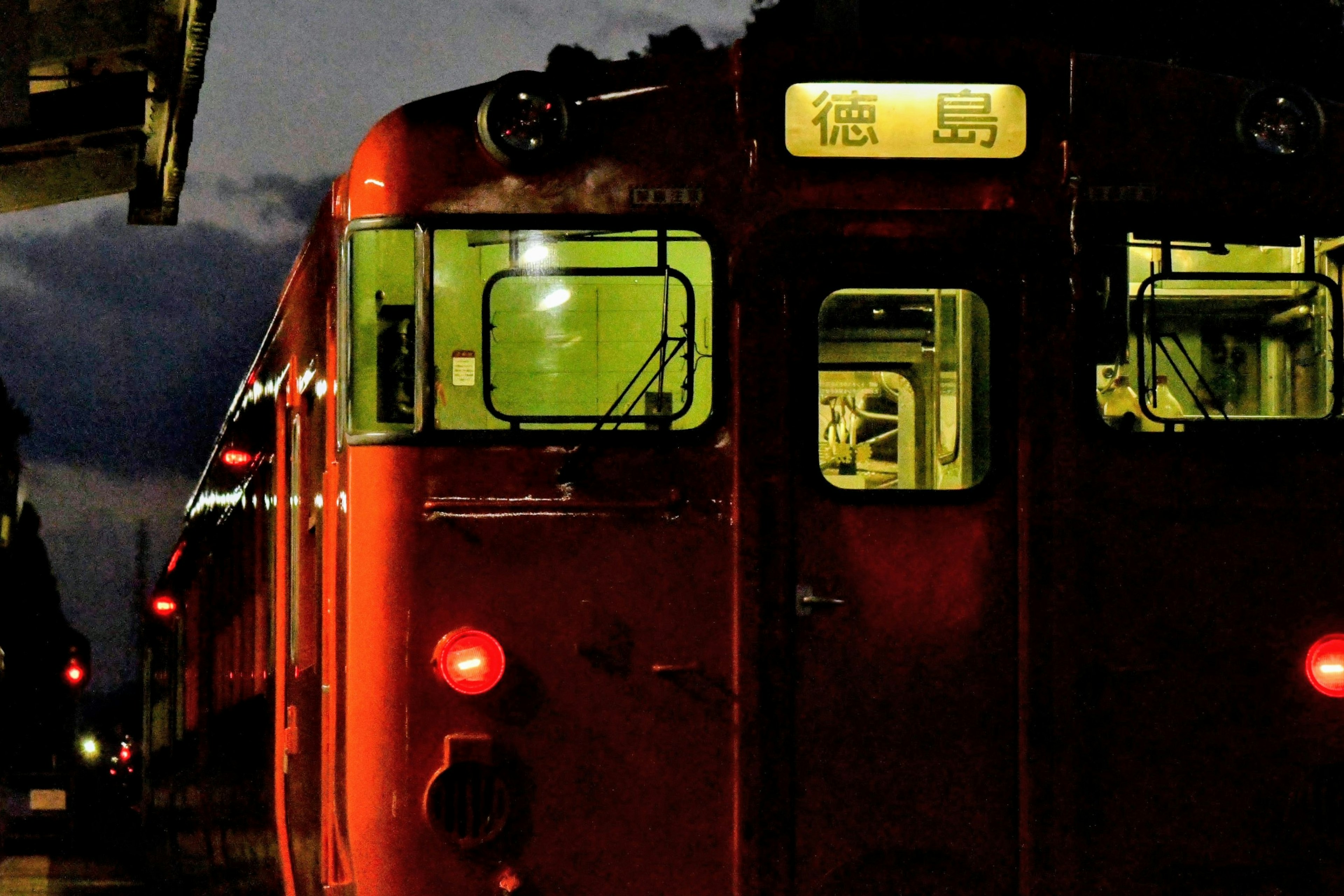 夜间停靠的红色火车，驾驶室灯光明亮，车站背景