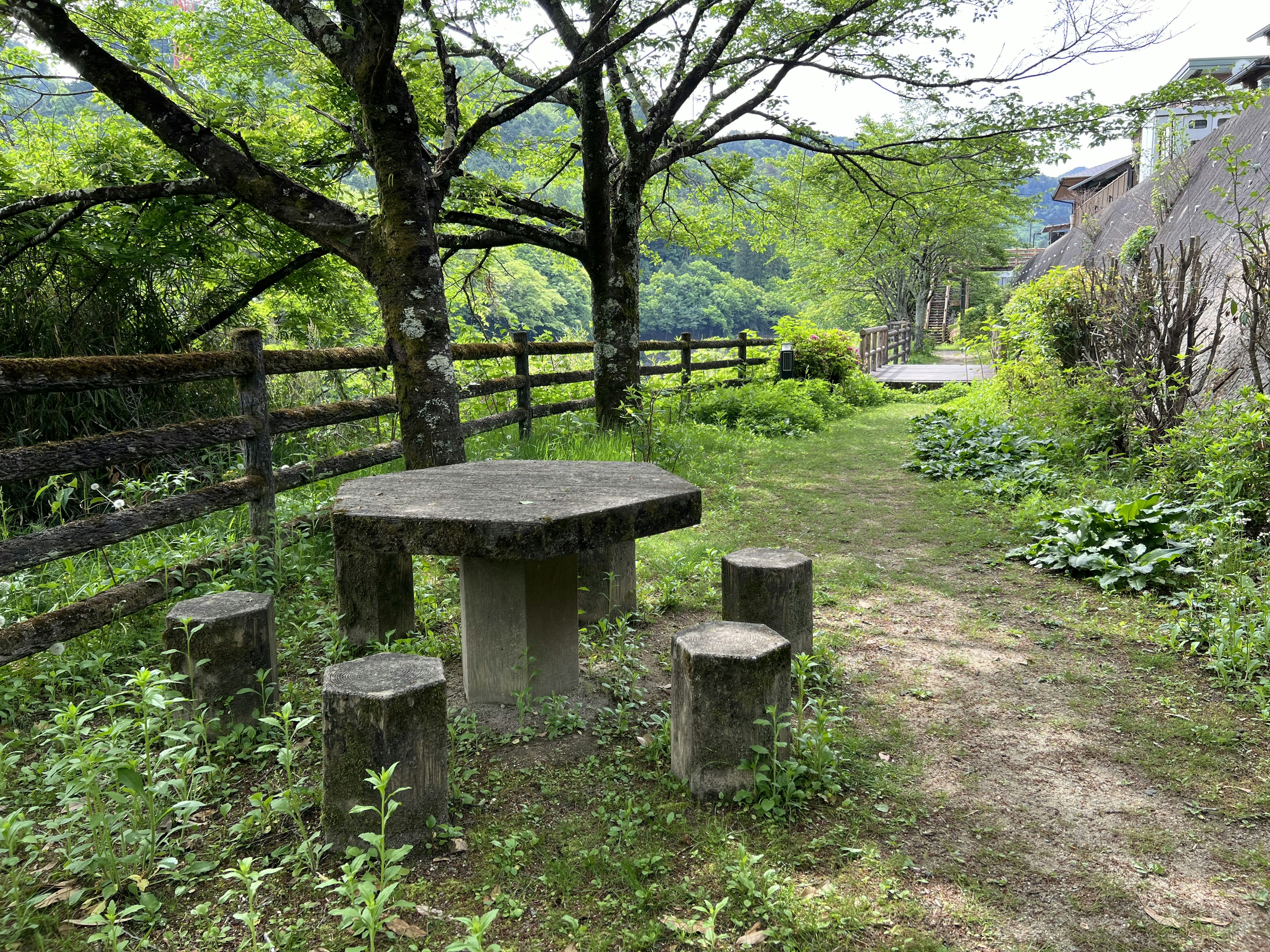 A serene landscape featuring a stone table and stools surrounded by greenery