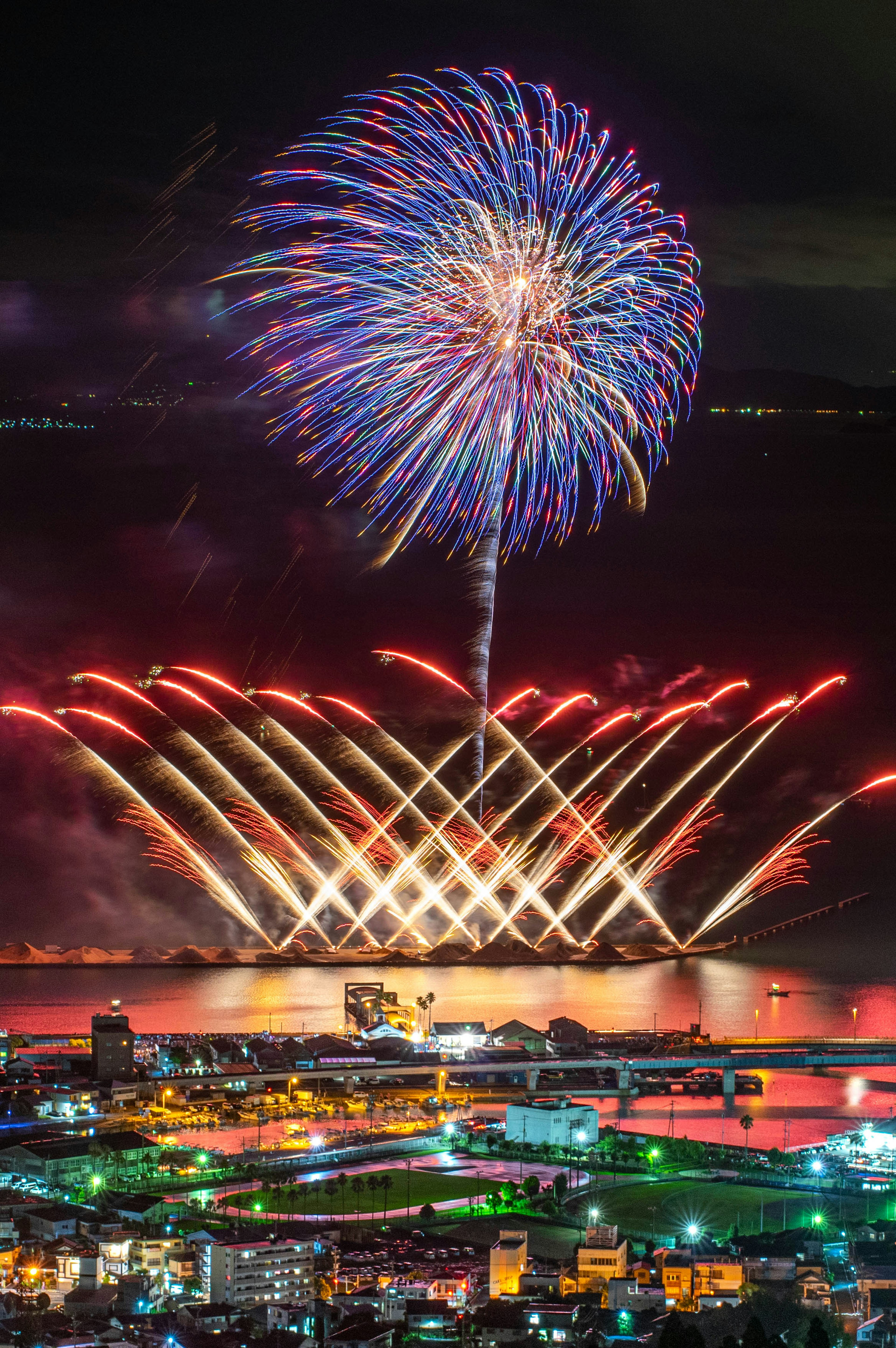 Fuochi d'artificio colorati che esplodono nel cielo notturno riflettendosi sull'acqua