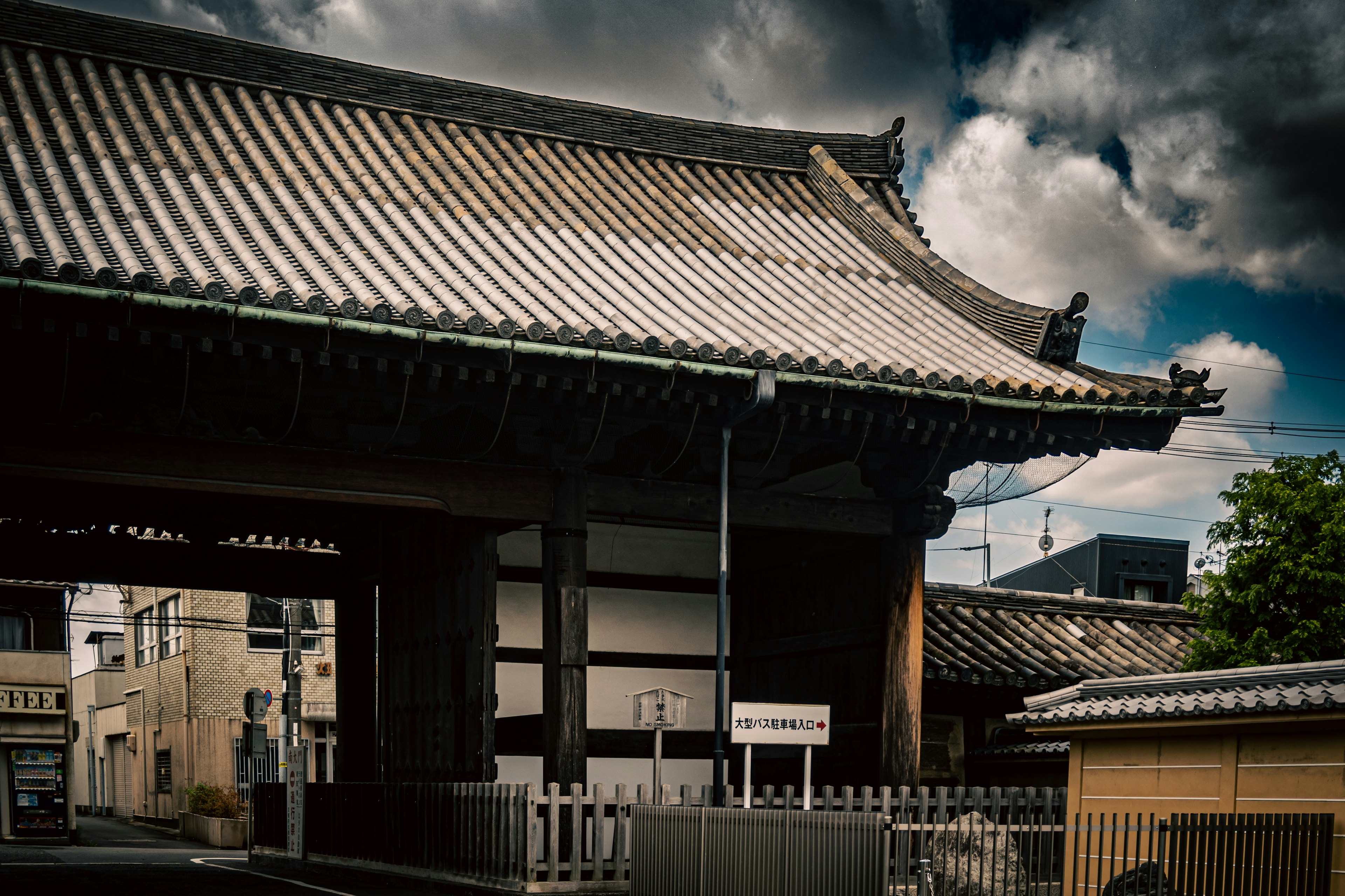 伝統的な日本の寺院の門、屋根の美しい曲線と瓦が特徴、暗い雲が背景にある