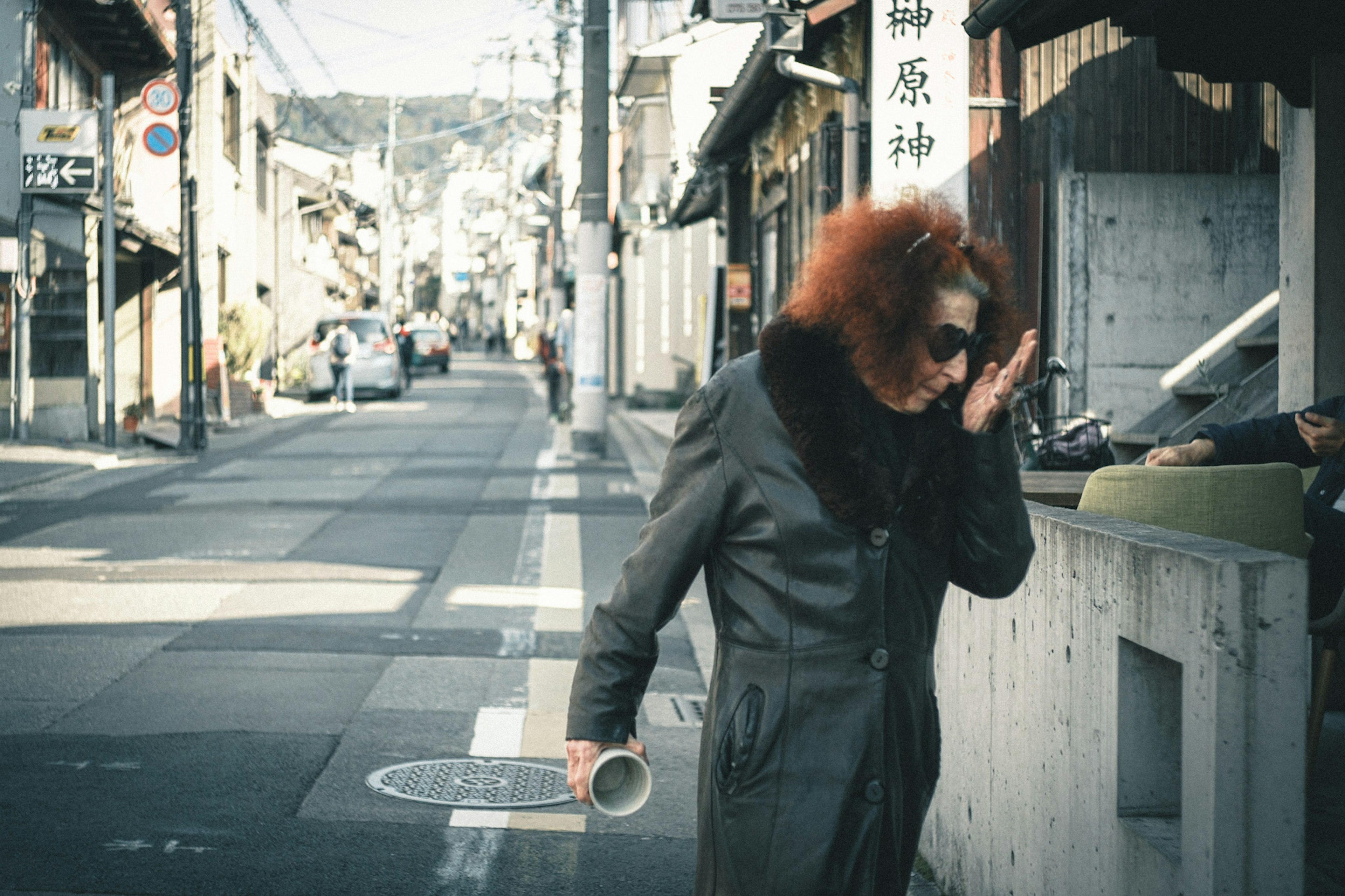 A woman with red hair walking down a street