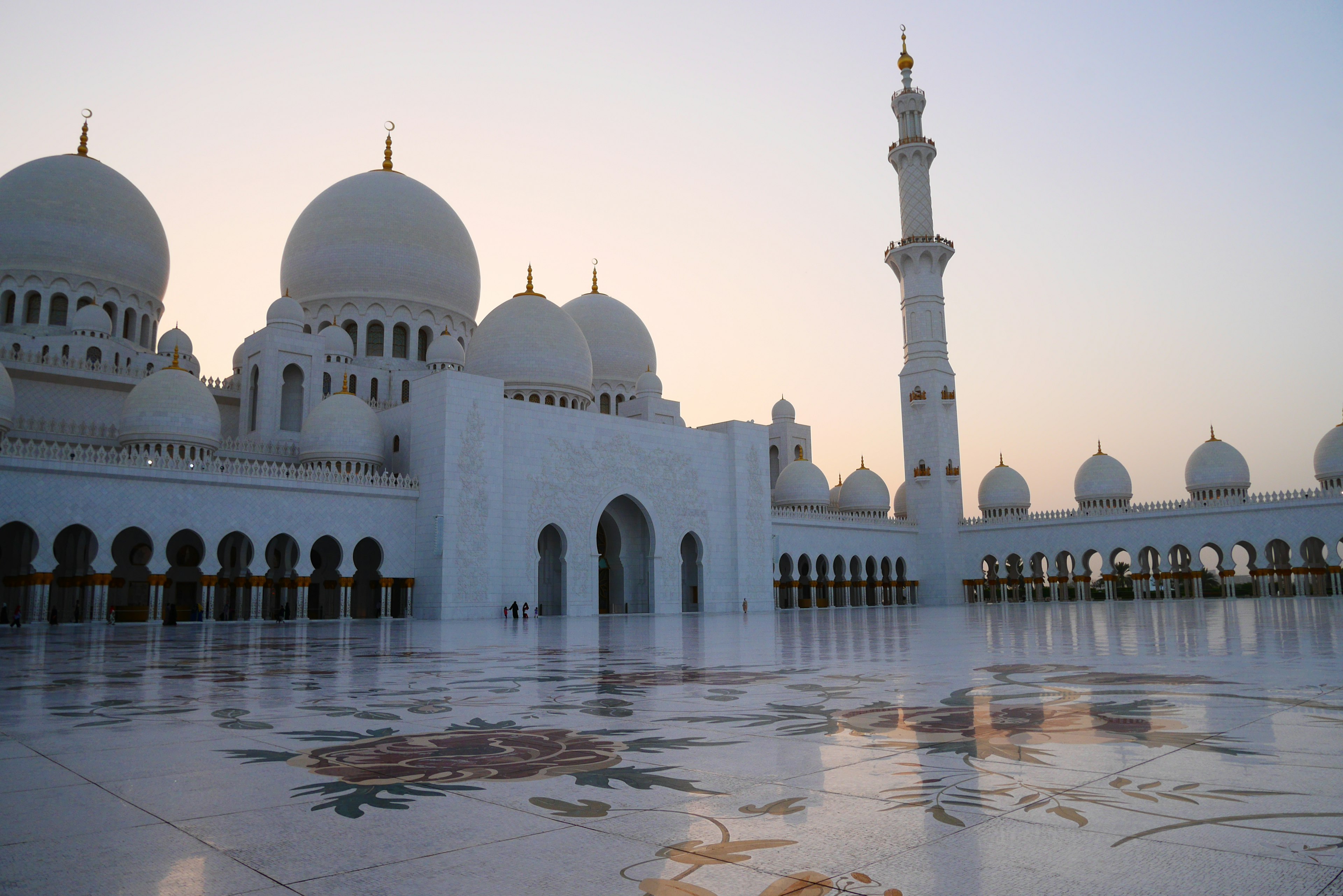 Grand white mosque exterior with beautiful domes and minaret