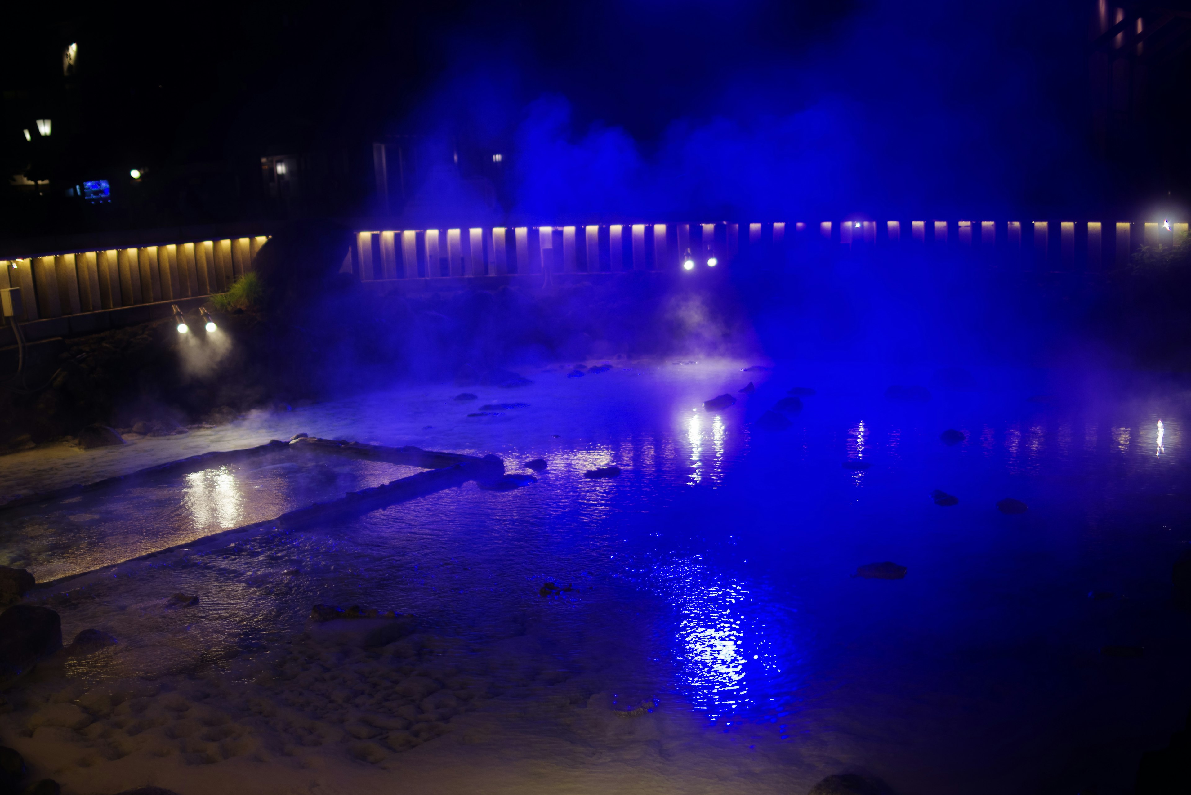 Night scene with blue lights reflecting on water surface and mist